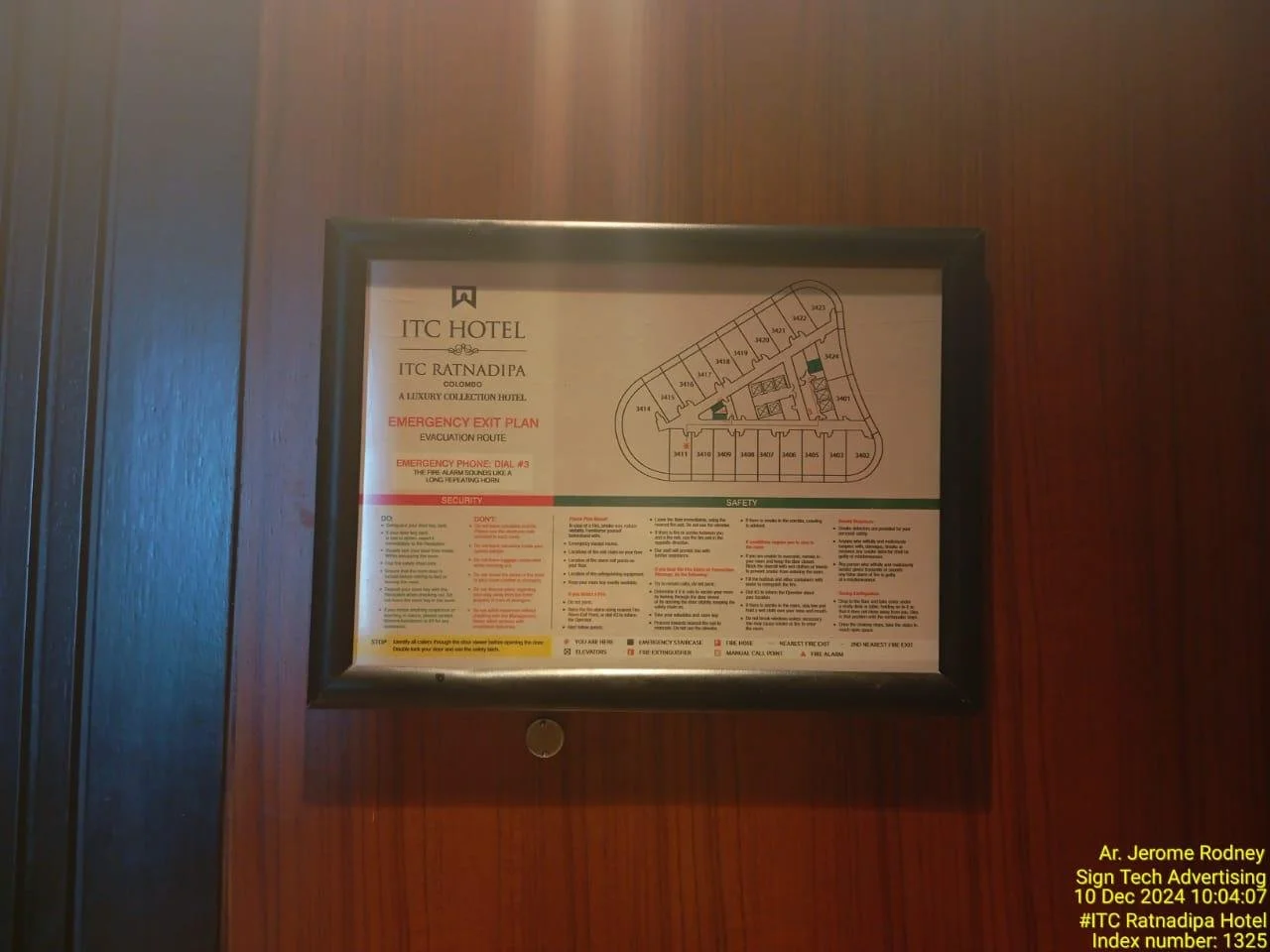 Hotel emergency exit plan and safety instructions framed on a wood-paneled wall.