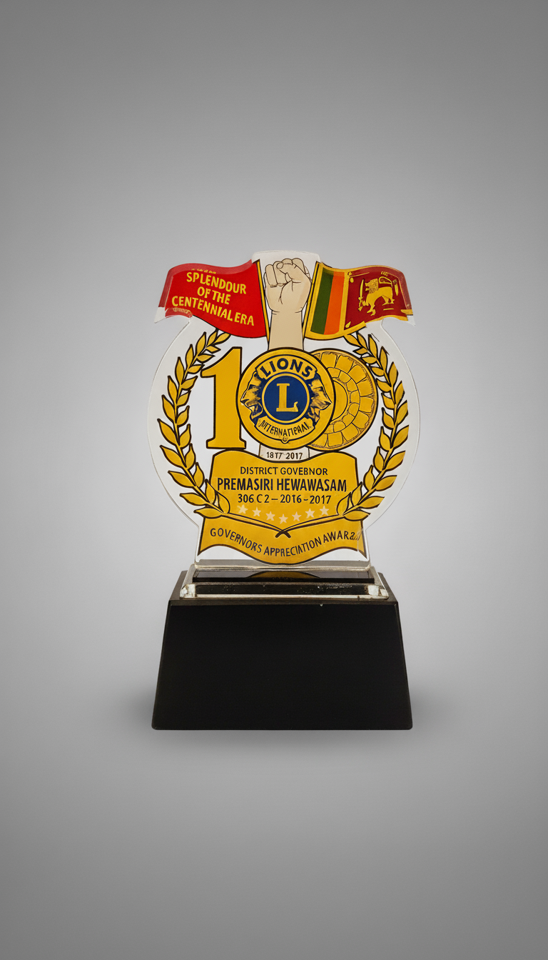 Lions International award trophy with a laurel wreath design, a raised fist, flags, and text celebrating the 10th anniversary and appreciation award for District Governor Premasiri Hewawasam from 2016 to 2017.
