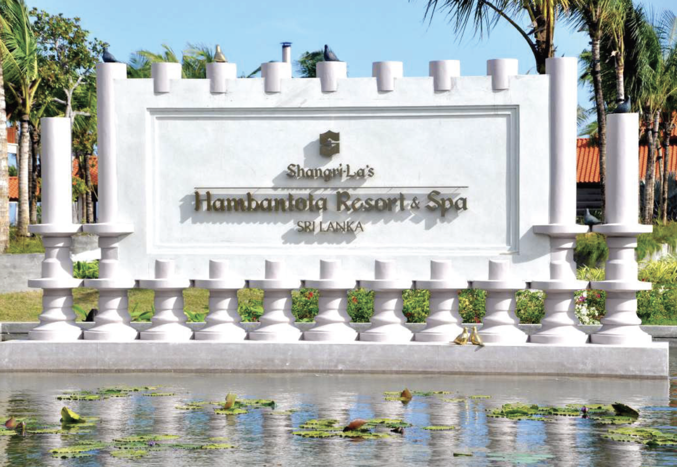 Sign at Shangri-La's Hambantota Resort & Spa in Sri Lanka with decorative columns and a pond with water lilies in the foreground.