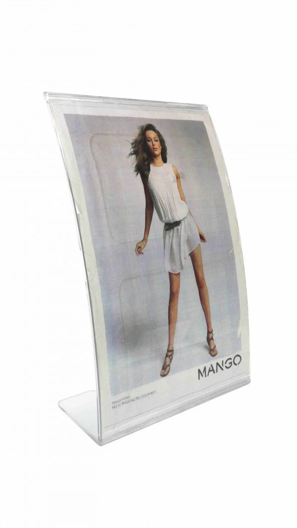 A clear acrylic display stand holding a fashion advertisement with a woman modeling a white outfit and high heels, and the brand name 'MANGO' at the bottom.