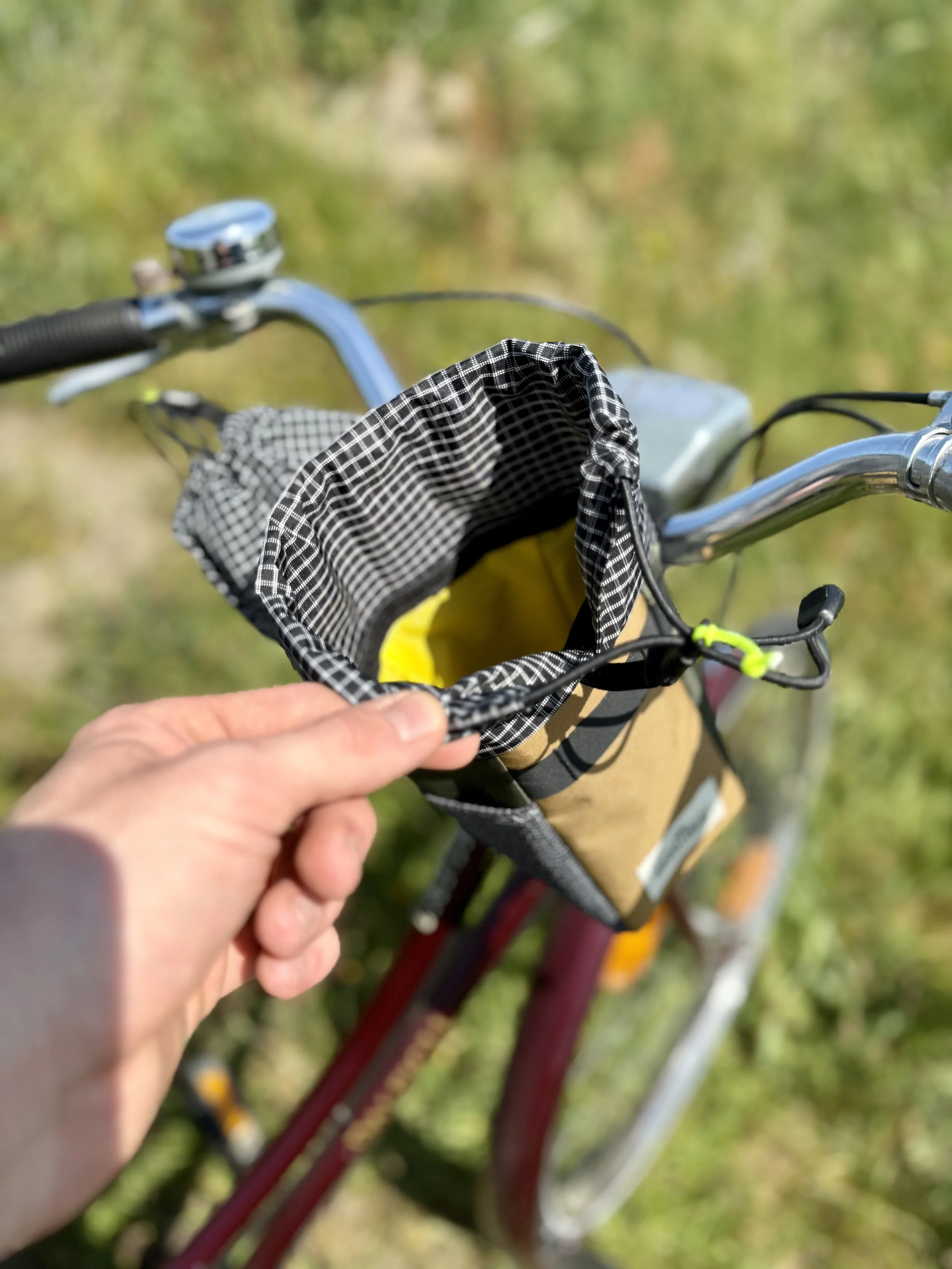 one hand opening a snack pouch handlebar bag with a colorful interior