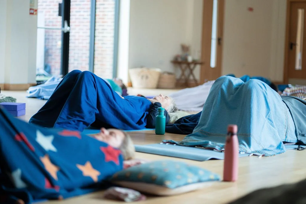 People relaxing in Yoga Nidra at a retreat