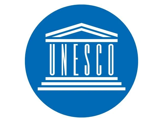 UNESCO logo featuring a white stylized classical building with columns on a blue circular background.