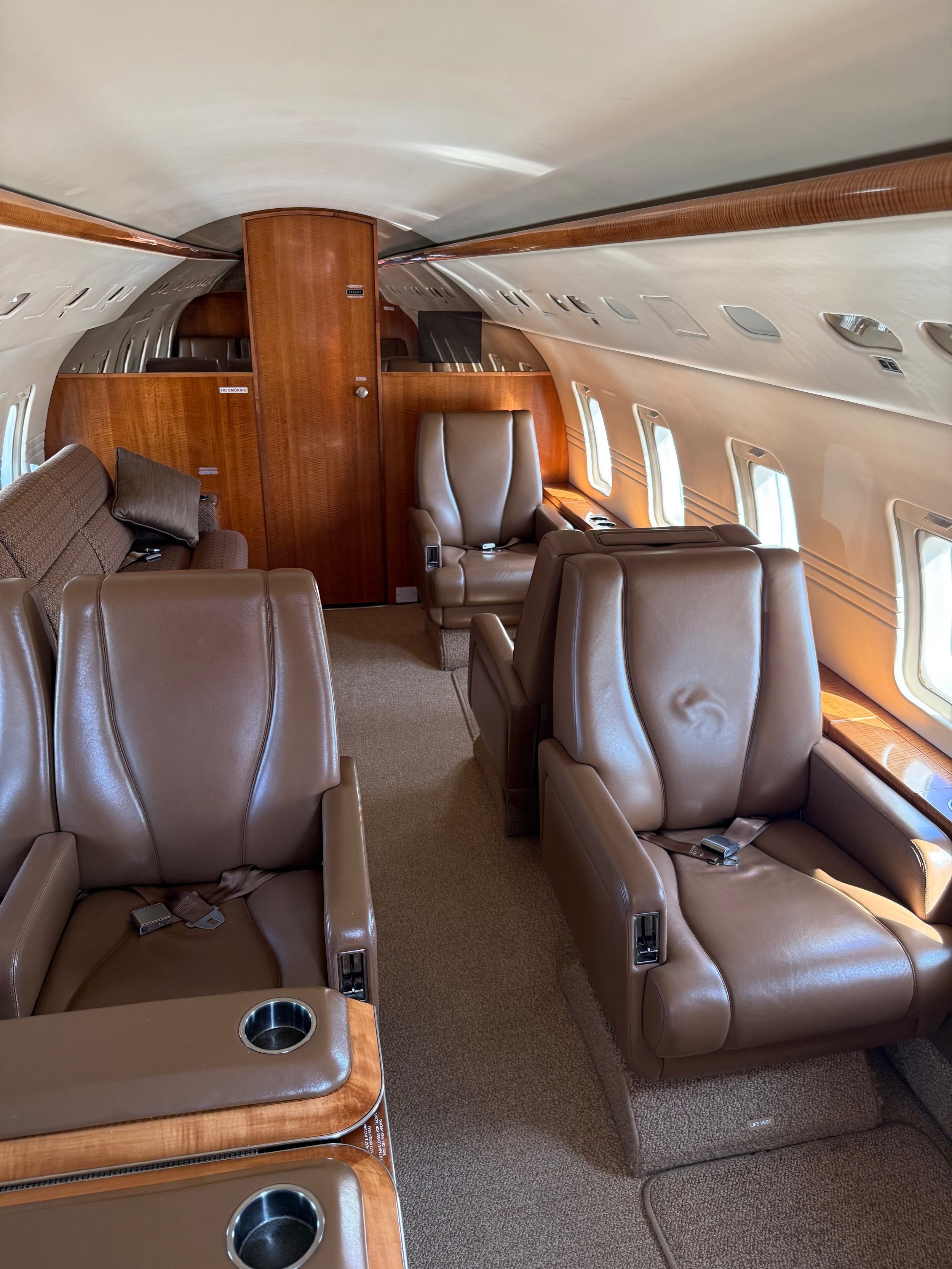 Interior of a private jet with brown leather seats and wood paneling
