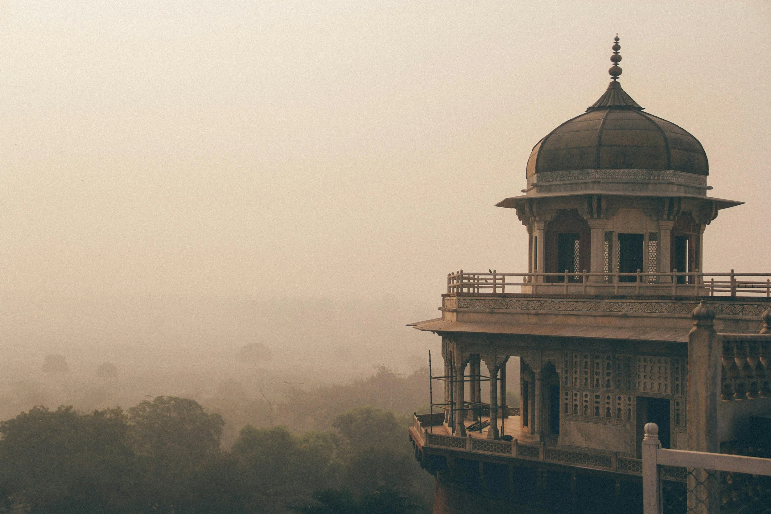 Historic building with dome and intricate architectural details against a hazy, misty landscape.