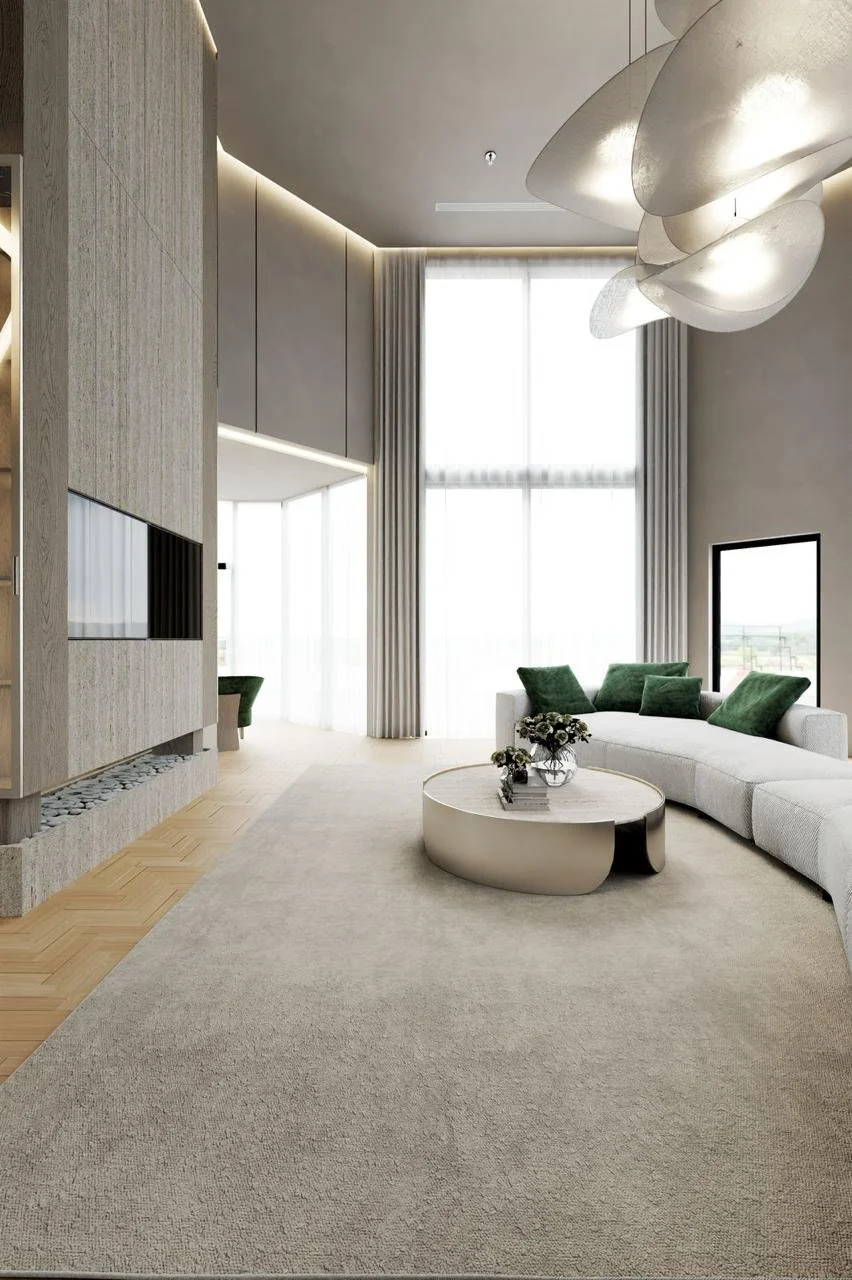 Modern living room with large windows, light gray sofa with green pillows, round coffee table, abstract ceiling light, and wooden accent wall.