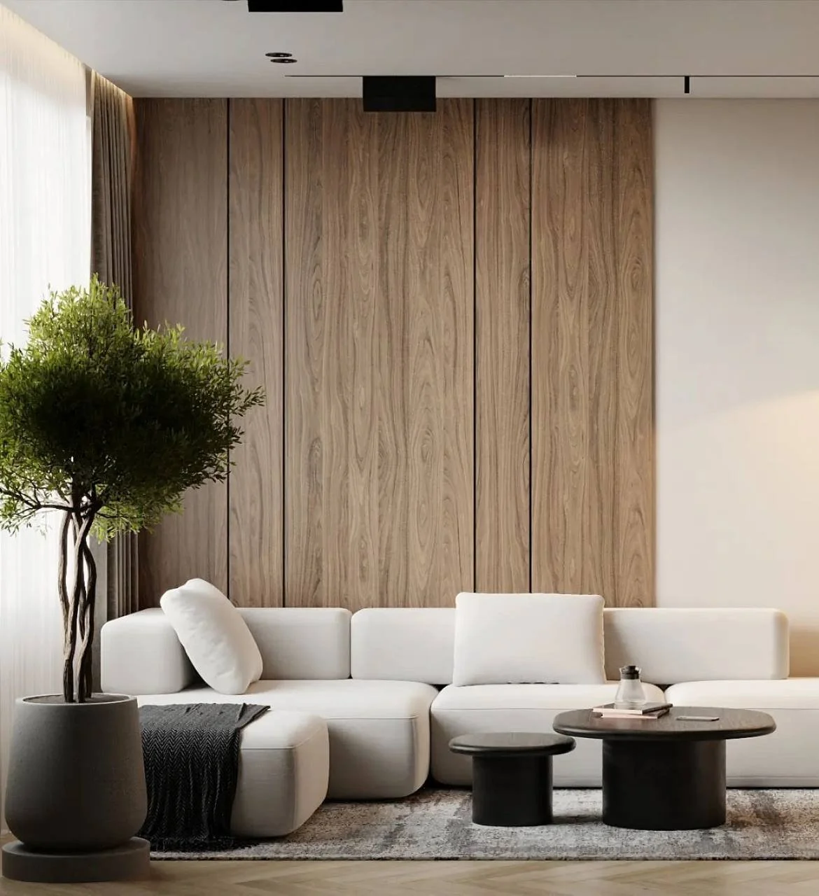 Modern living room with white sectional sofa, round coffee tables, potted plant, and wood-paneled wall.