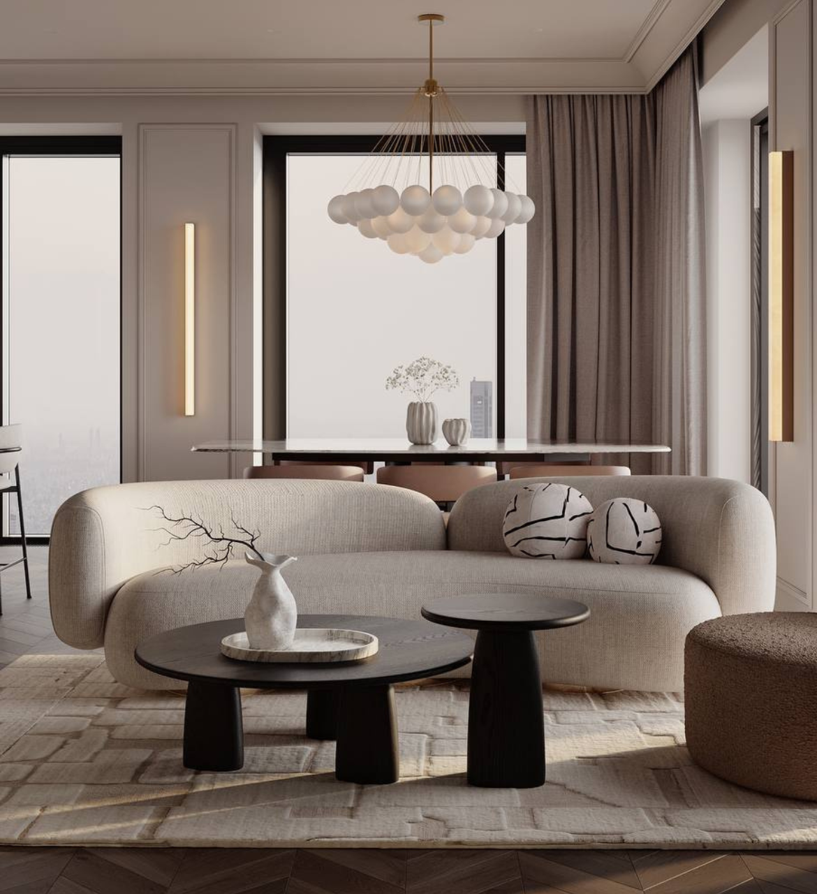 Modern living room with beige sofa, round black coffee tables, decorative cushions, contemporary chandelier, and large windows with gray curtains.
