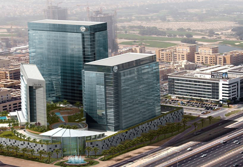 Aerial view of a modern business complex with tall glass skyscrapers and surrounding greenery.