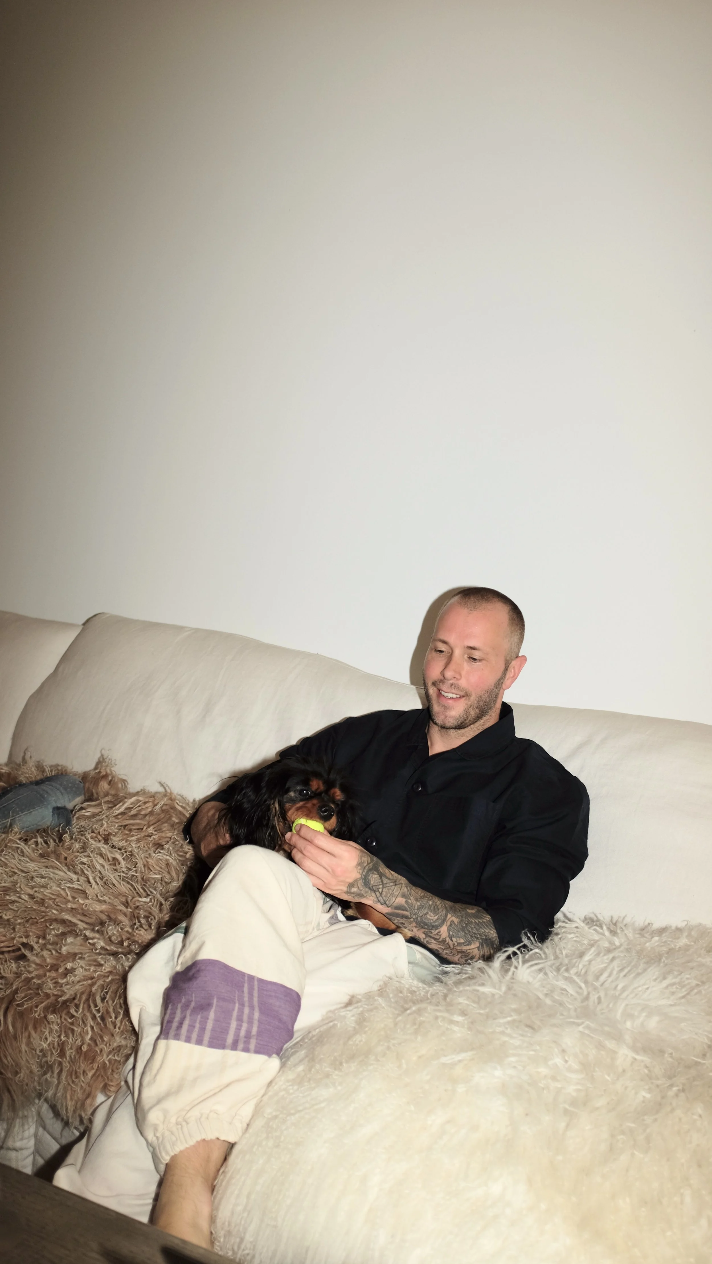 Mike Bagale sitting on the couch wearing black chef coat designed by Finery.