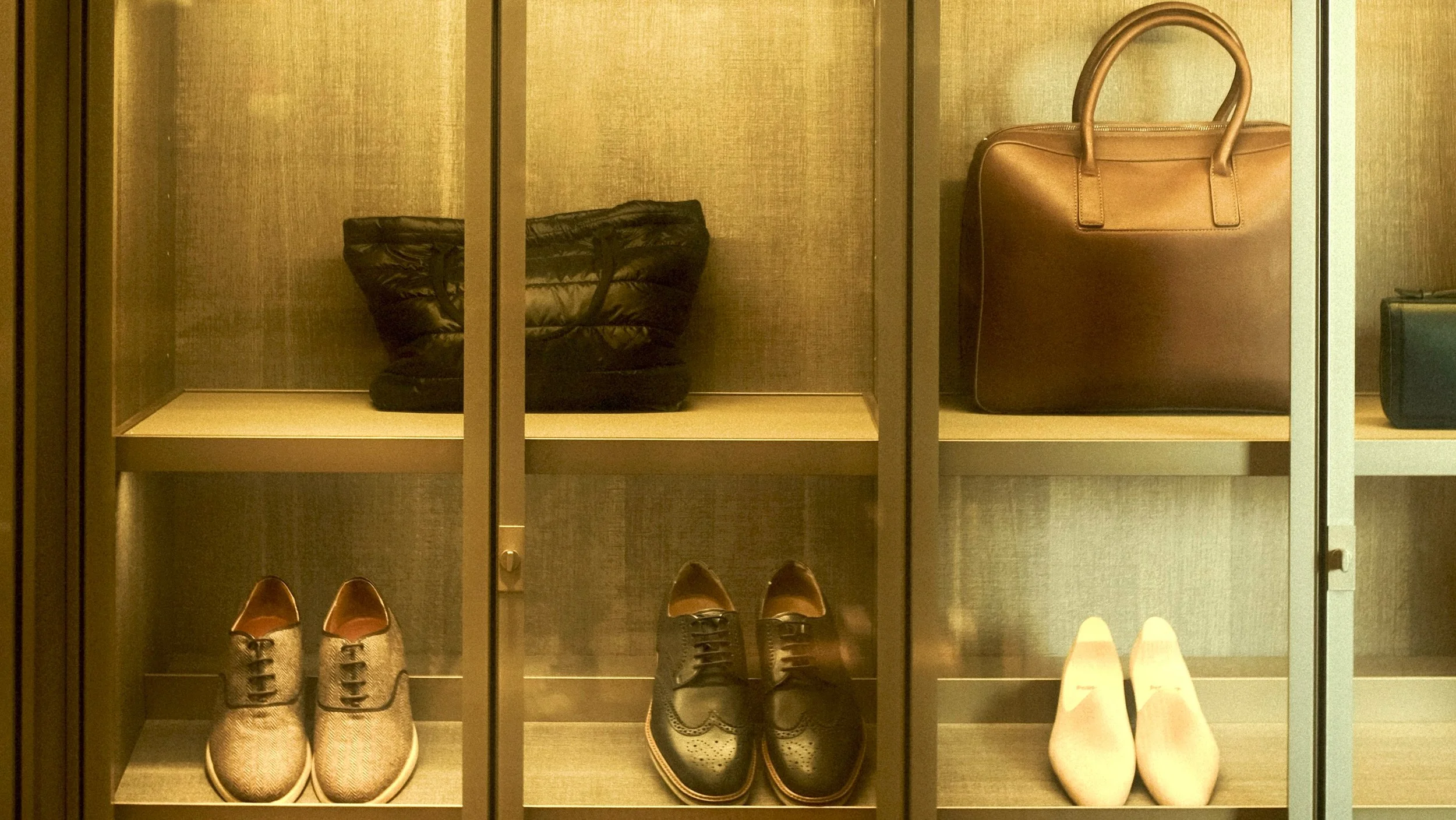 Des chaussures, un sac en cuir, une paire de bottes en brou de noix et un sac à main en cuir dans une vitrine.