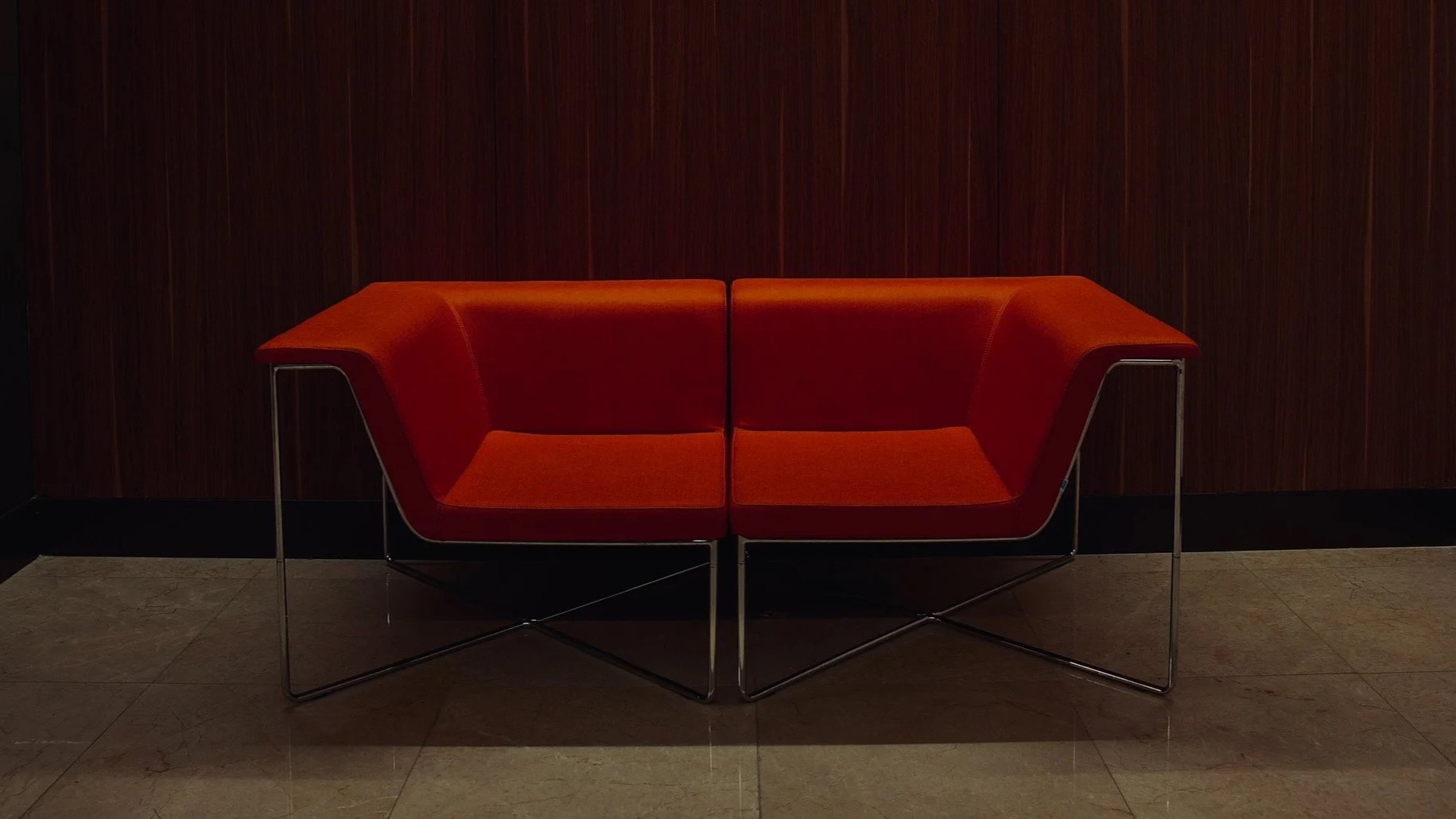 Banc rouge moderne contre un mur en bois foncé.