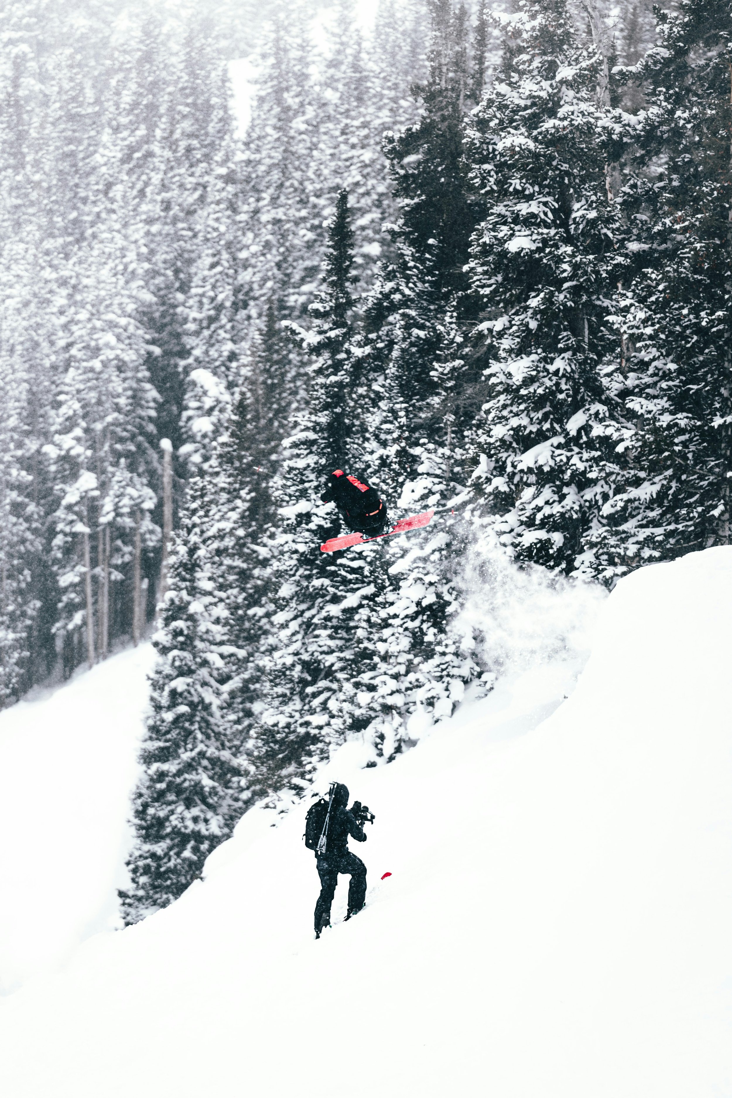 A skier jumping off a snowy ramp in a forested area covered in snow.
