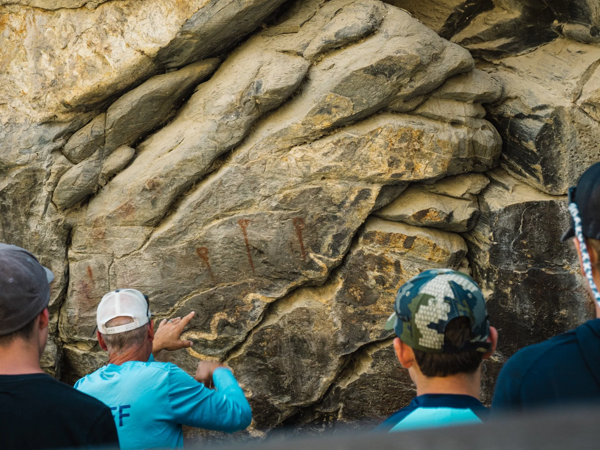 Campers observe petroglyphs on a rock wall