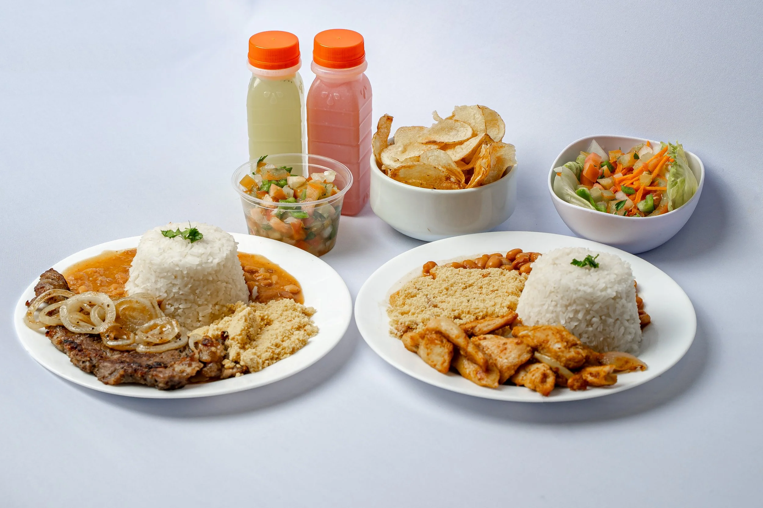 Pratos típicos brasileiros com arroz, feijão, carne, salada, chips, e molhos