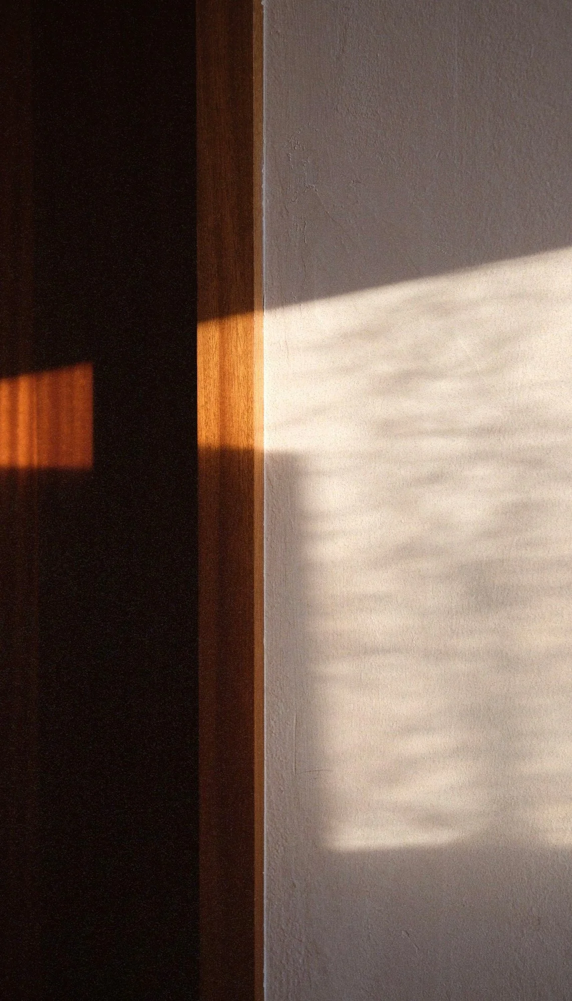 Schatten und Licht auf einer weißen Wand neben einer Holzleiste