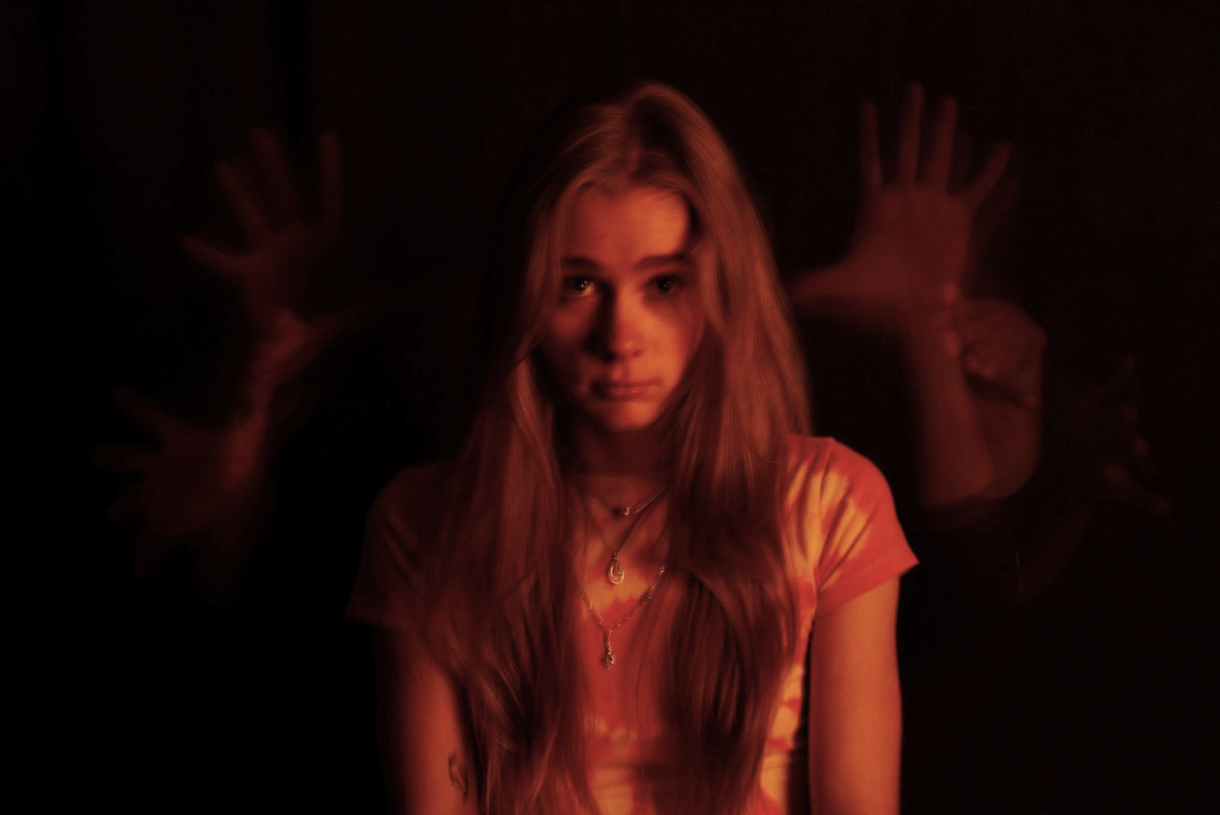 woman with ominous floating hands behind her head