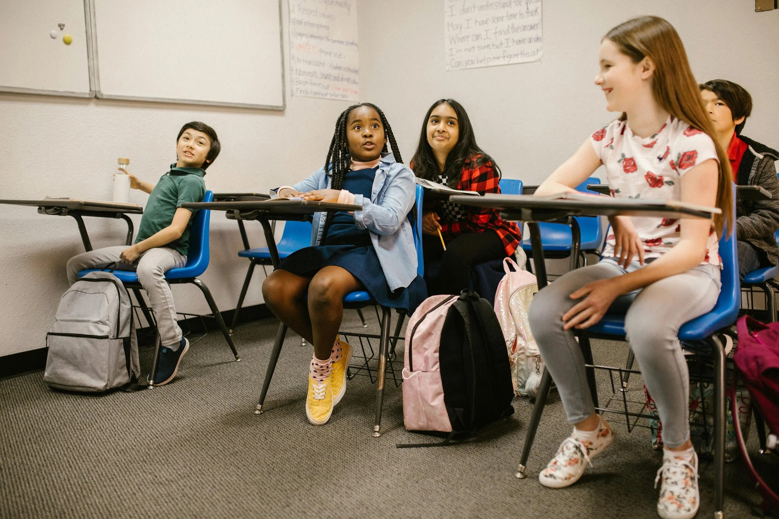A group of diverse students sitting in a classroom participating in a class discussion.