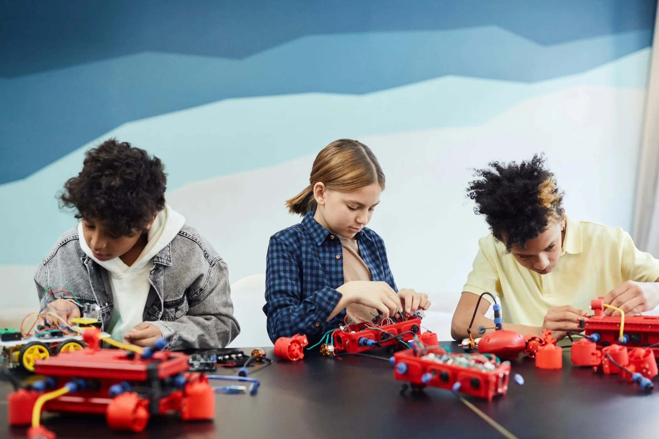 Three middle school students working on robotics projects in a classroom setting, learning and engaging.