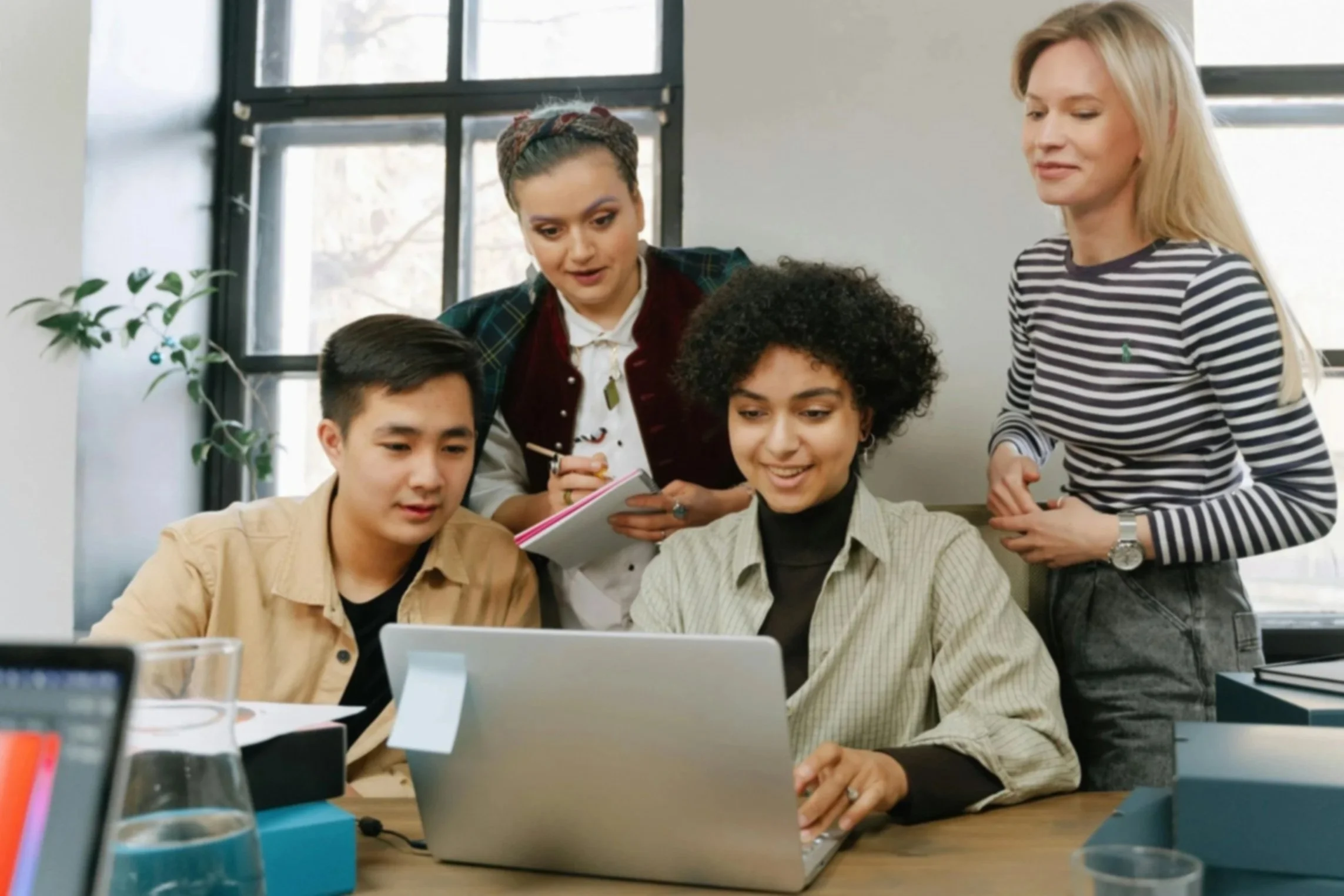A group of teachers collaborating around a computer screen, sharing ideas and strategies in a bright, welcoming workspace.