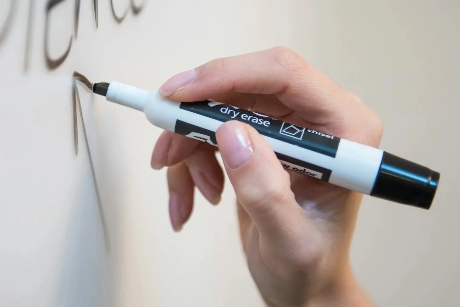 Close-up of a teacher writing on a classroom whiteboard.