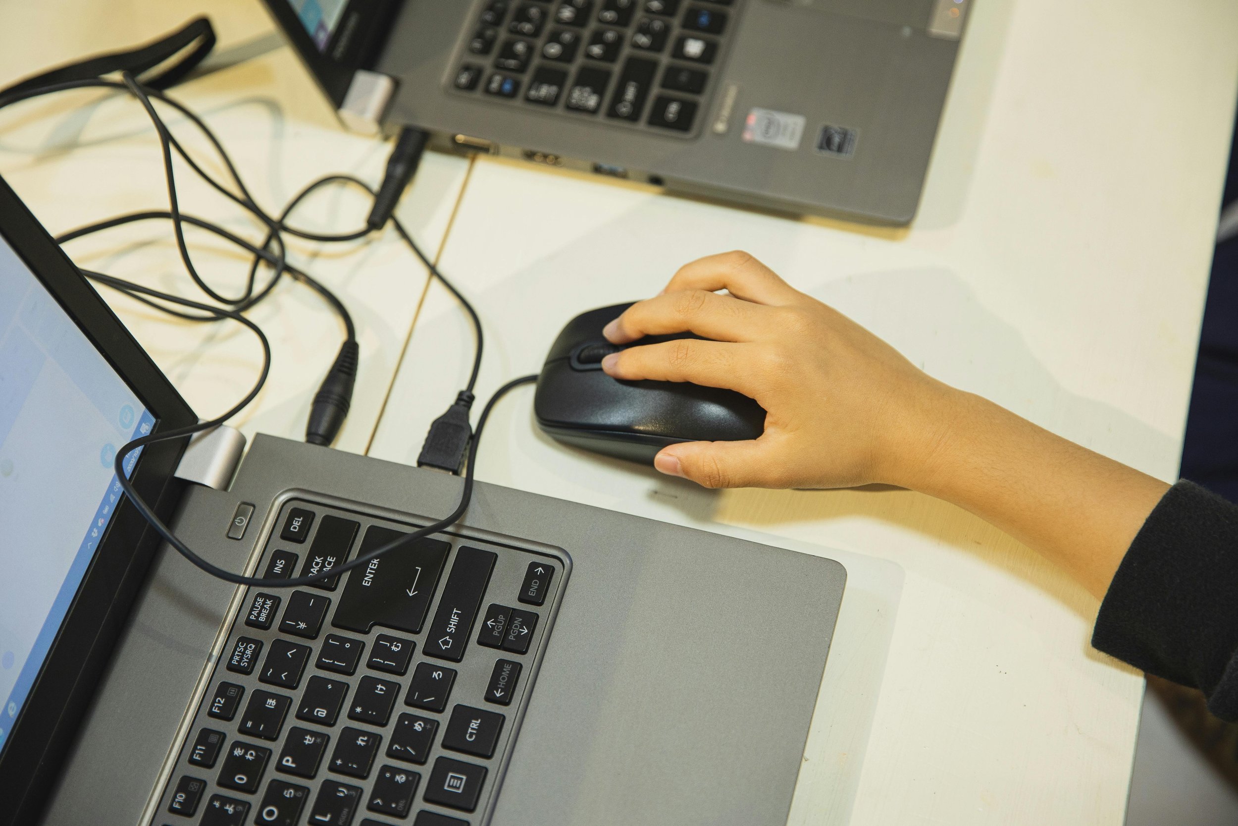 A close up of a young student’s hand on a mouse while using a school computer.
