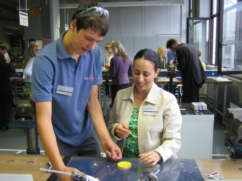 Dr. Allende working alongside a German student during a vocational school visit. 