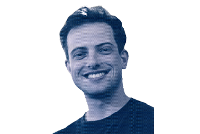 A smiling young man with short, dark hair in a black shirt against a blue gradient background.