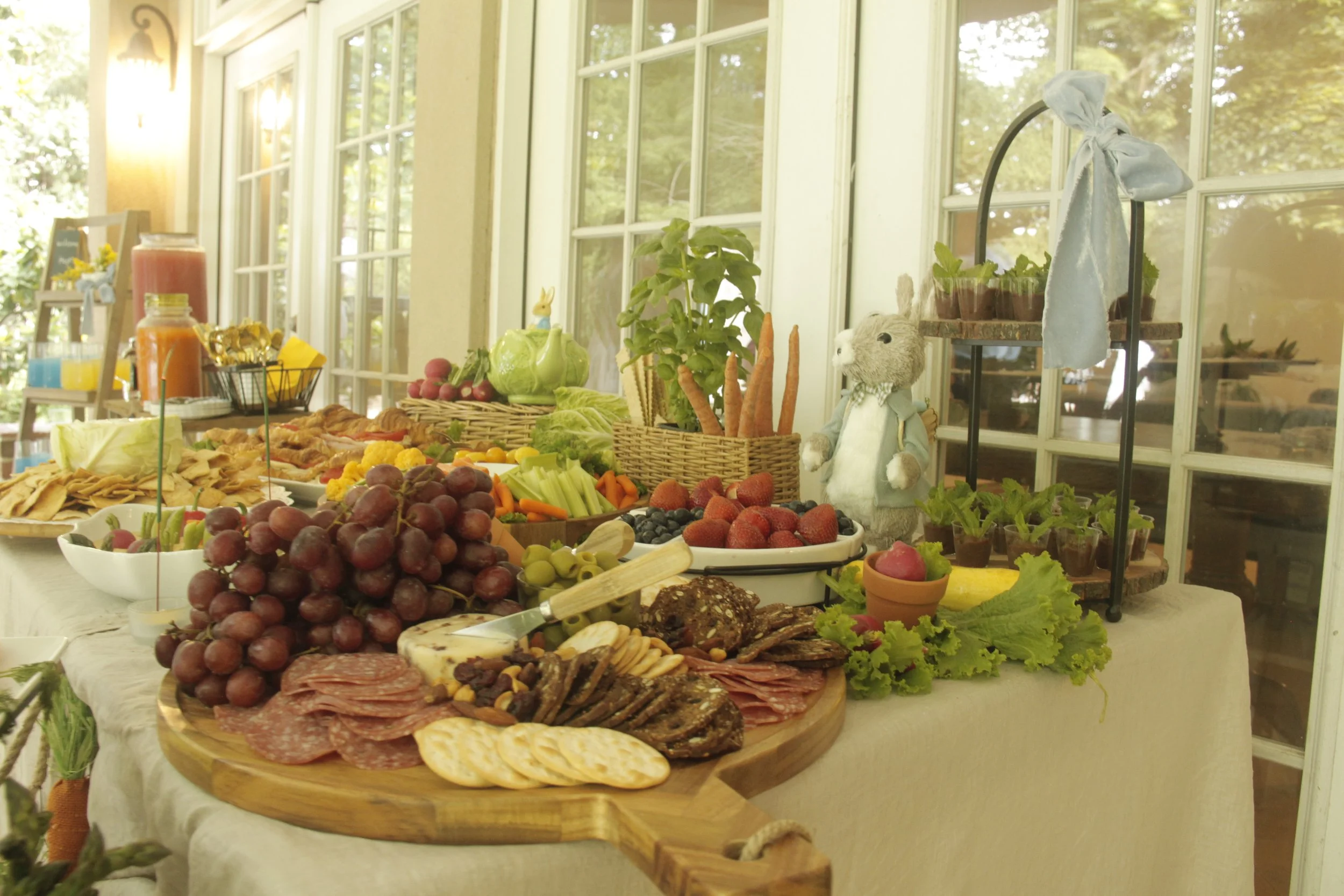 Our beautifully curated Peter Rabbit-inspired grazing table is a feast for both the eyes and taste buds. Overflowing with fresh fruits, artisanal cheeses, charcuterie, crisp vegetables, and gourmet crackers, this charming spread is styled with whimsi
