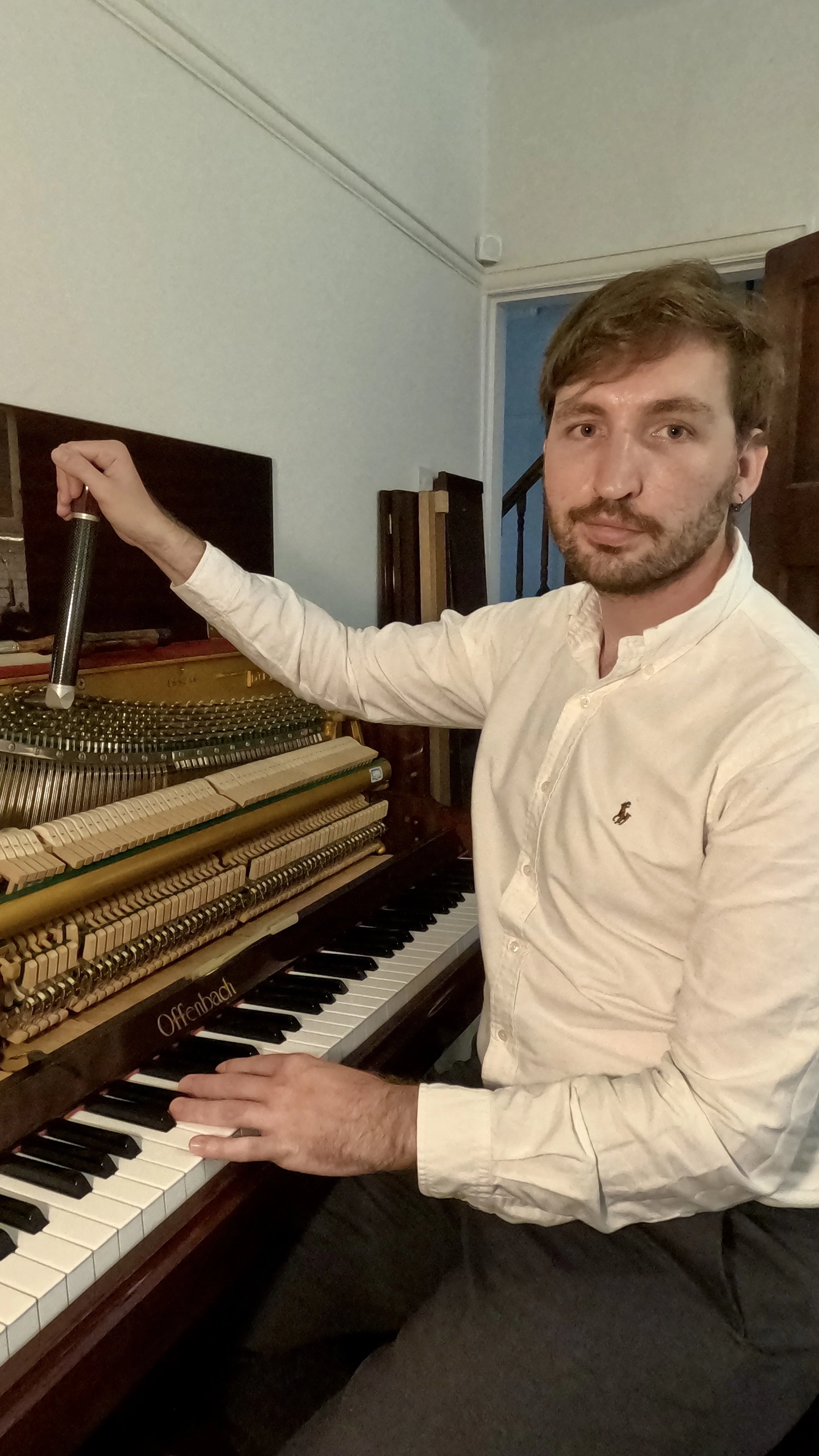 .A man tuning a piano in a white shirt