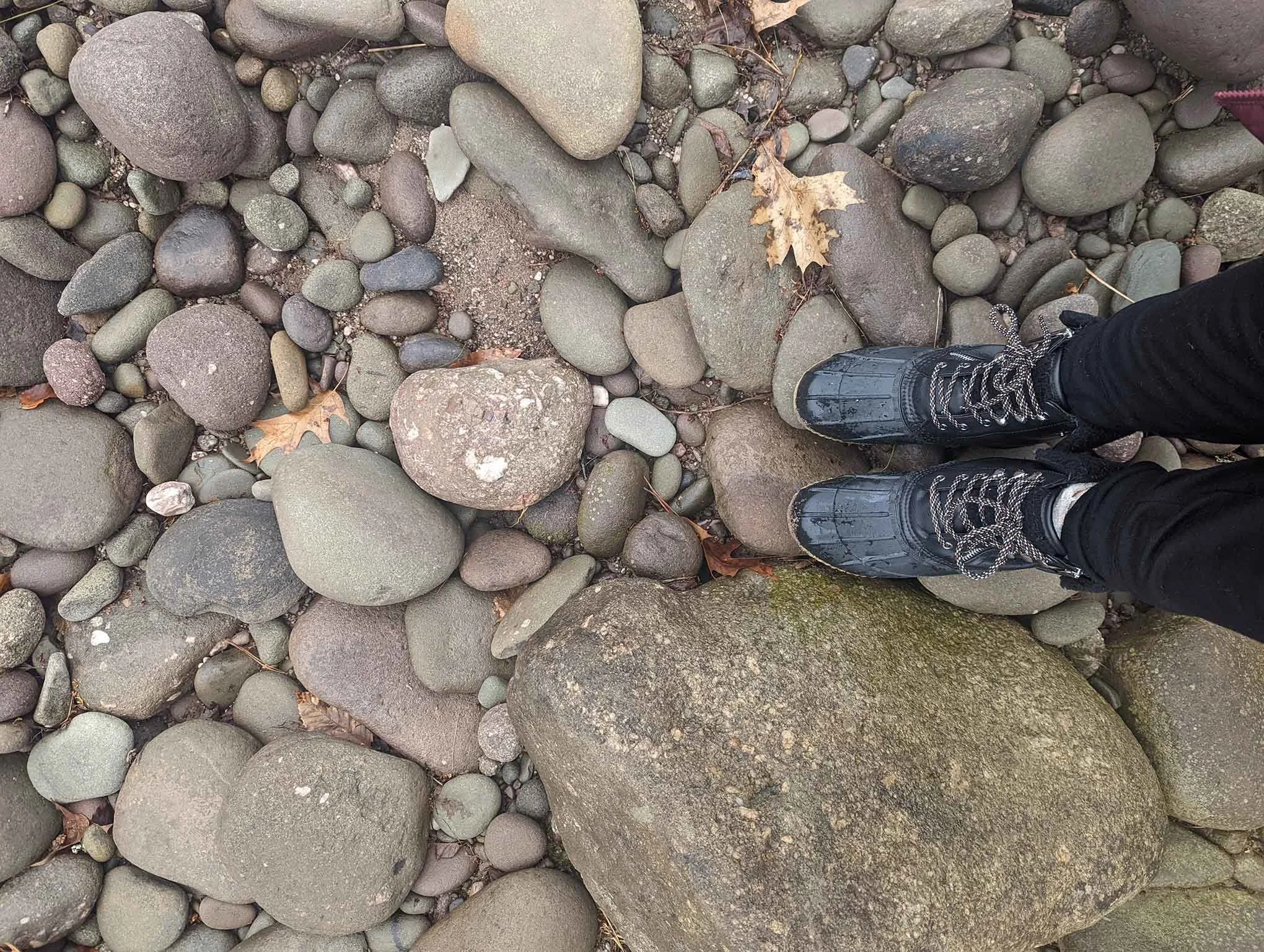 Feet standing on smooth river stones symbolizing grounding and inner balance during Parts Work Therapy at Illuminated Pathways, Philadelphia, Pennsylvania.