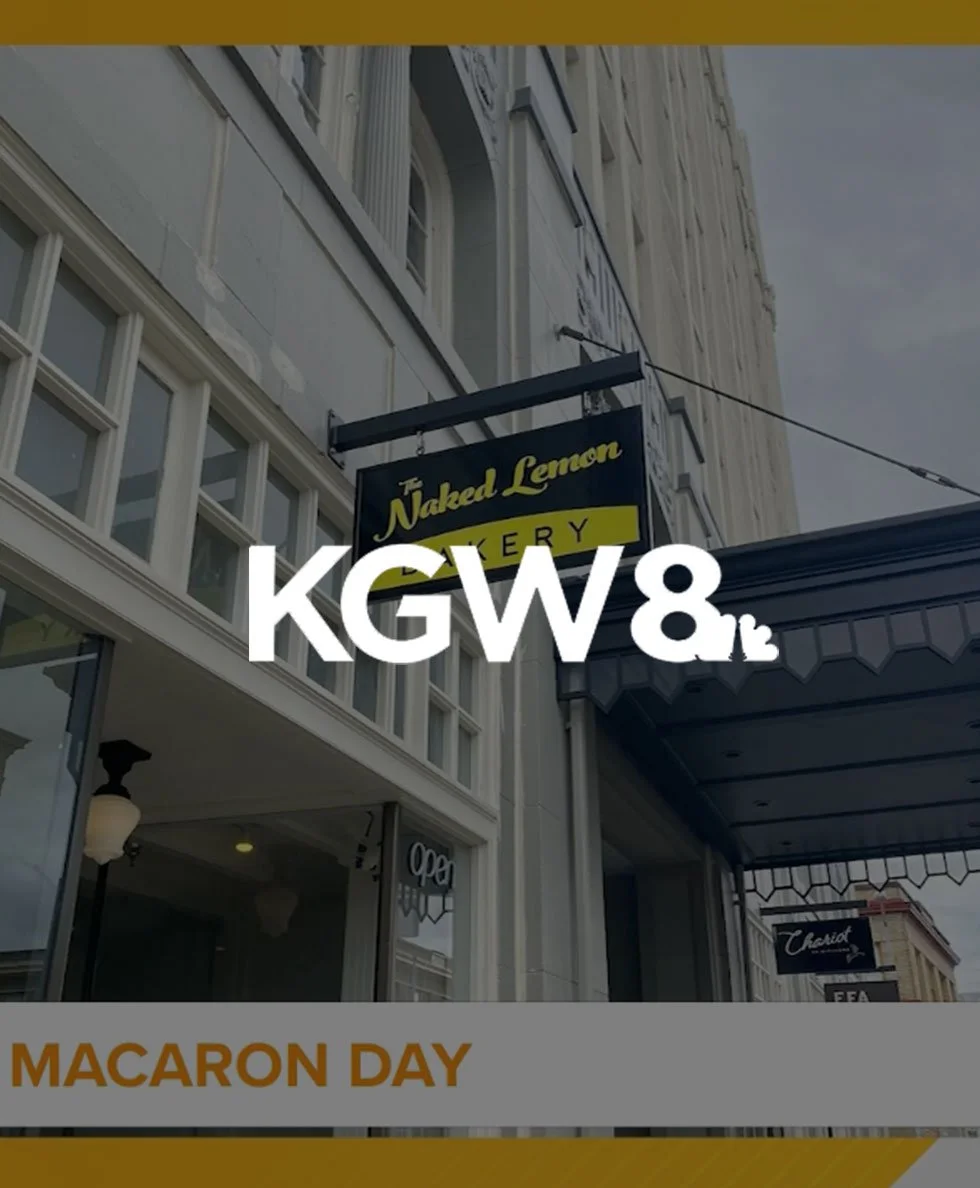 Sign for The Naked Lemon Bakery on a building exterior with KGW8 logo and text reading 'Macaron Day.'