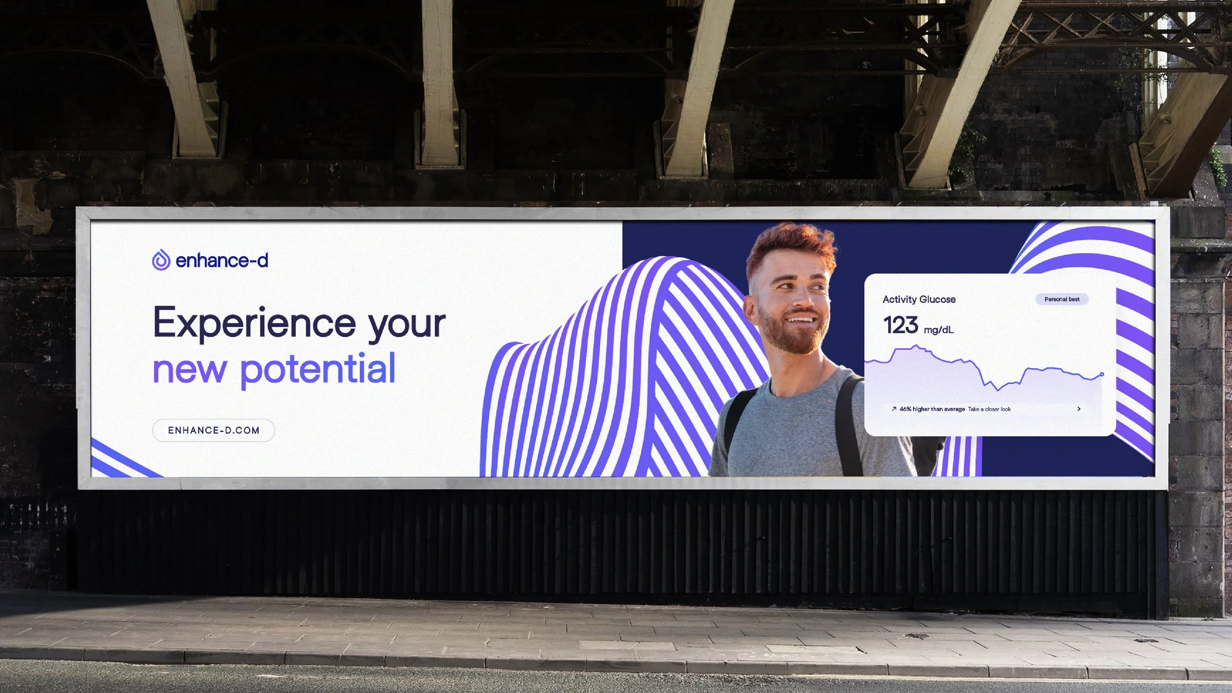 Billboard advertisement for a health monitoring company called enhance-d. It features a smiling young man with a backpack, a stylized striped graphic, and a small health data graph showing blood glucose levels.