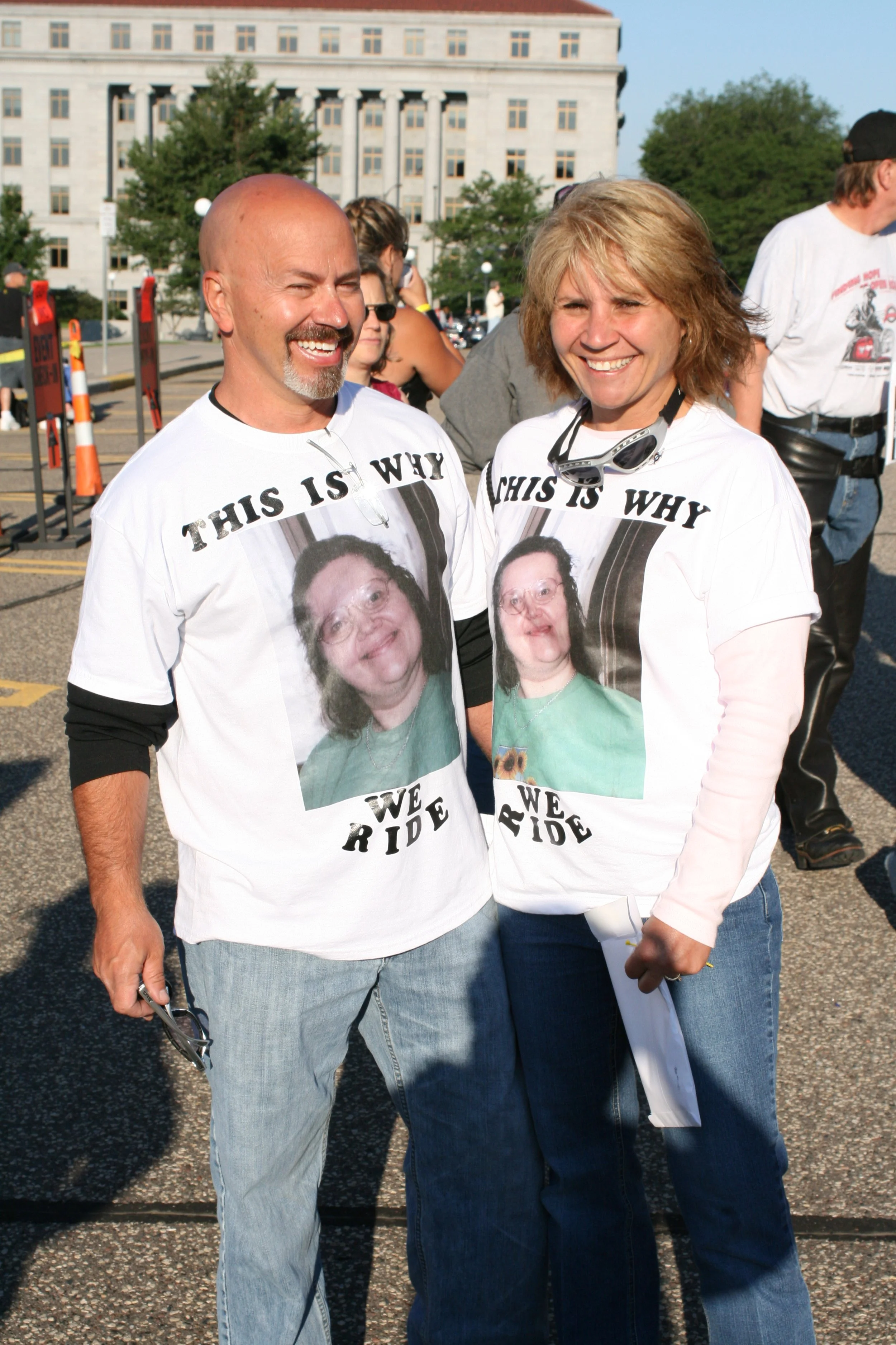 Two participants wearing "This is why we ride" shirts with a picture of a family member on them