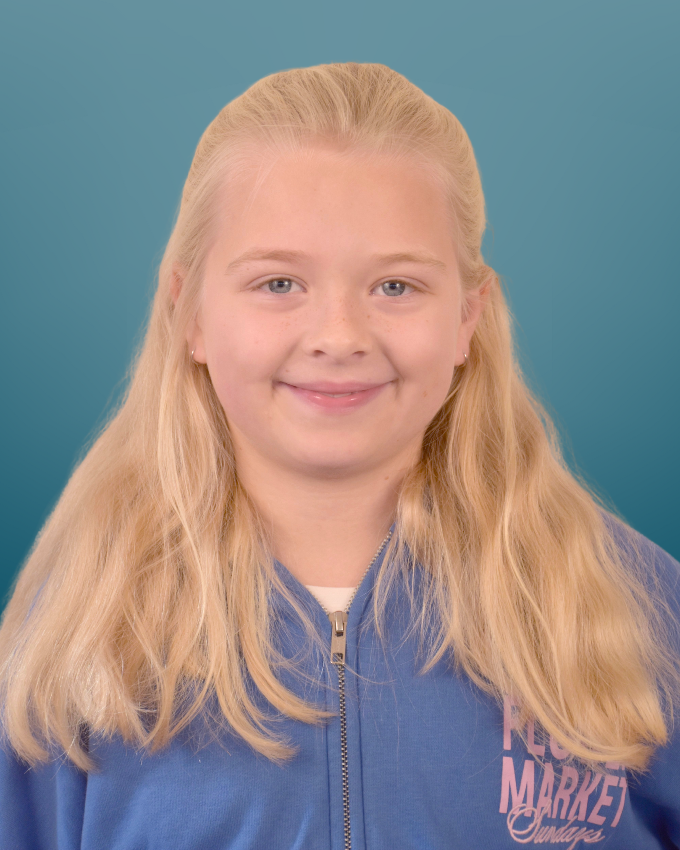 A young girl with long blonde hair, blue eyes, and a light smile, wearing a blue zip-up jacket with pink text on the chest, against a blue gradient background.