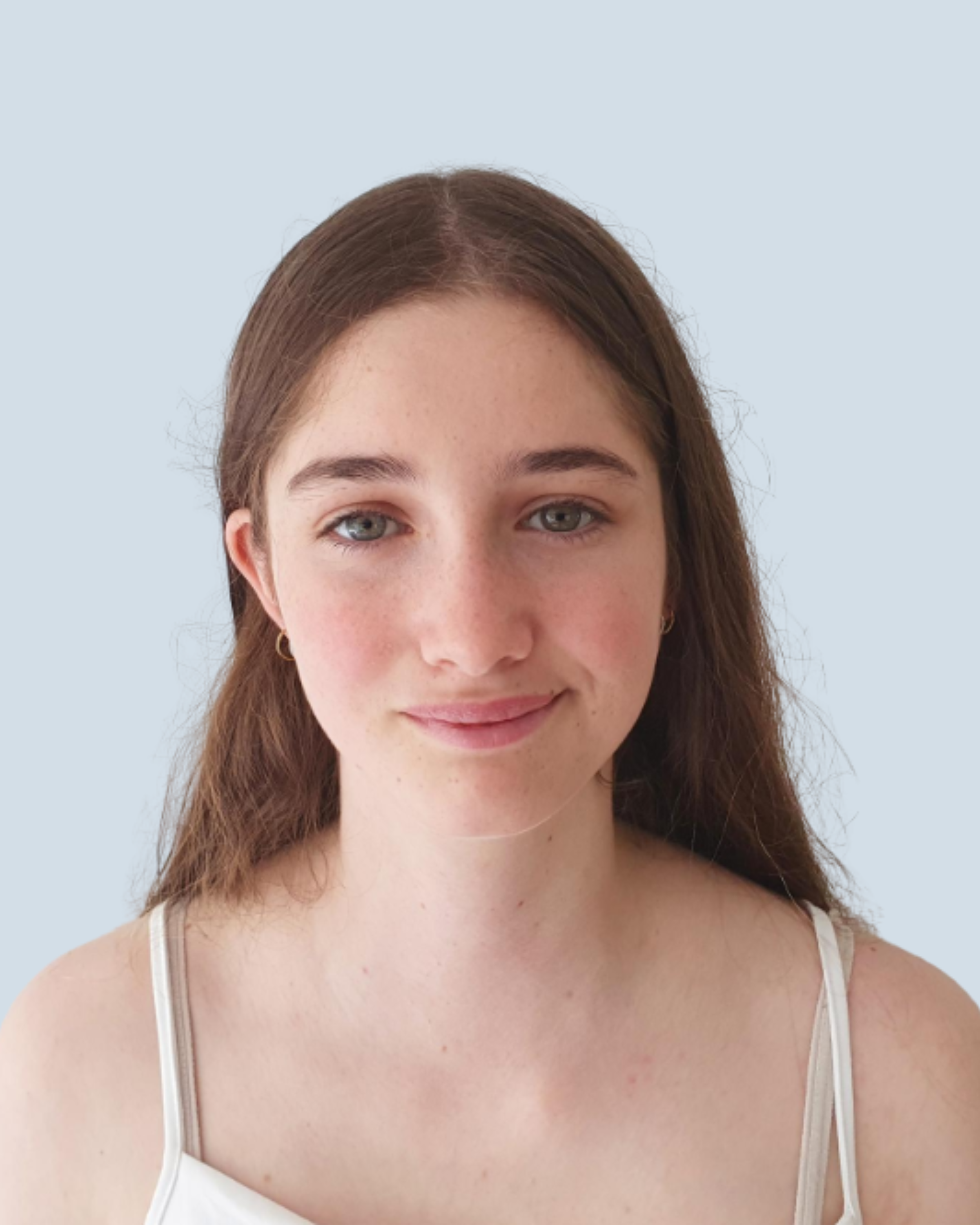 A young woman with long brown hair, blue eyes, and fair skin, smiling softly, wearing a white tank top, against a plain light blue background.