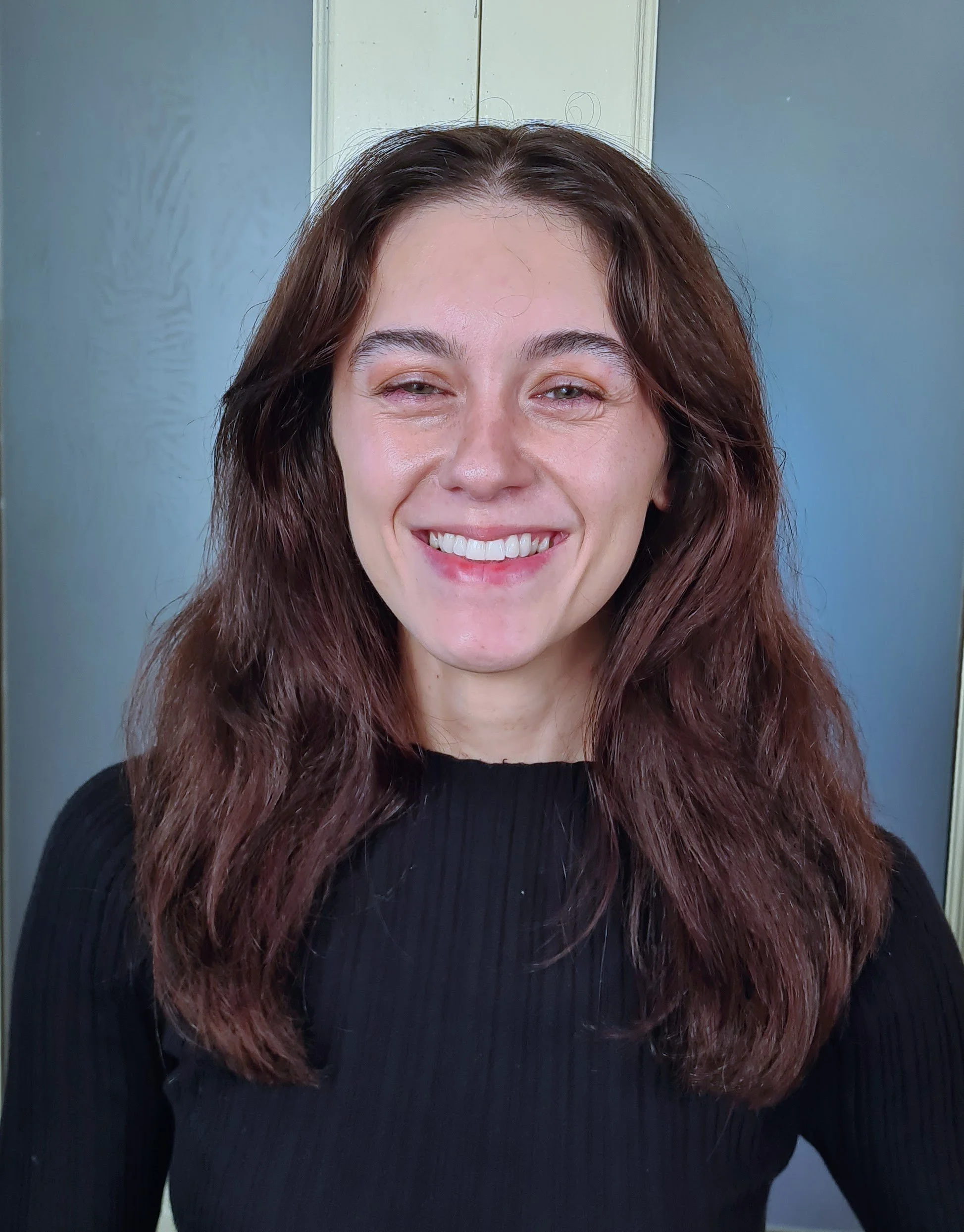 A young woman with long dark hair wearing a gray t-shirt against a plain white background.
