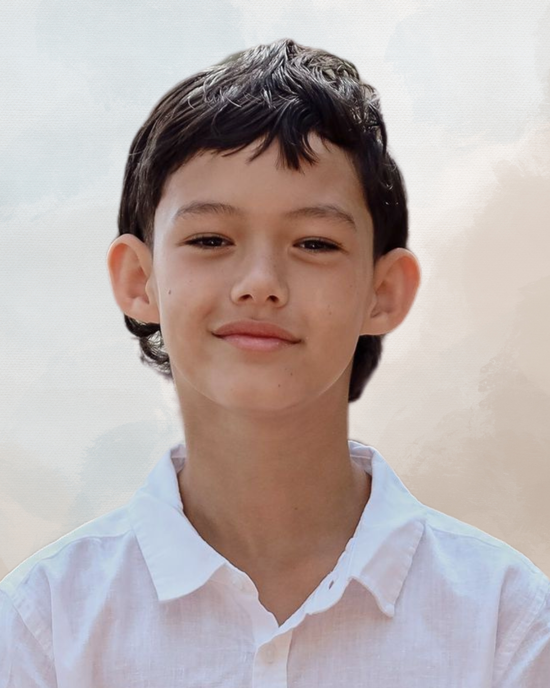 Close-up of a smiling young boy with dark hair wearing a white shirt, standing outdoors against a cloudy sky.