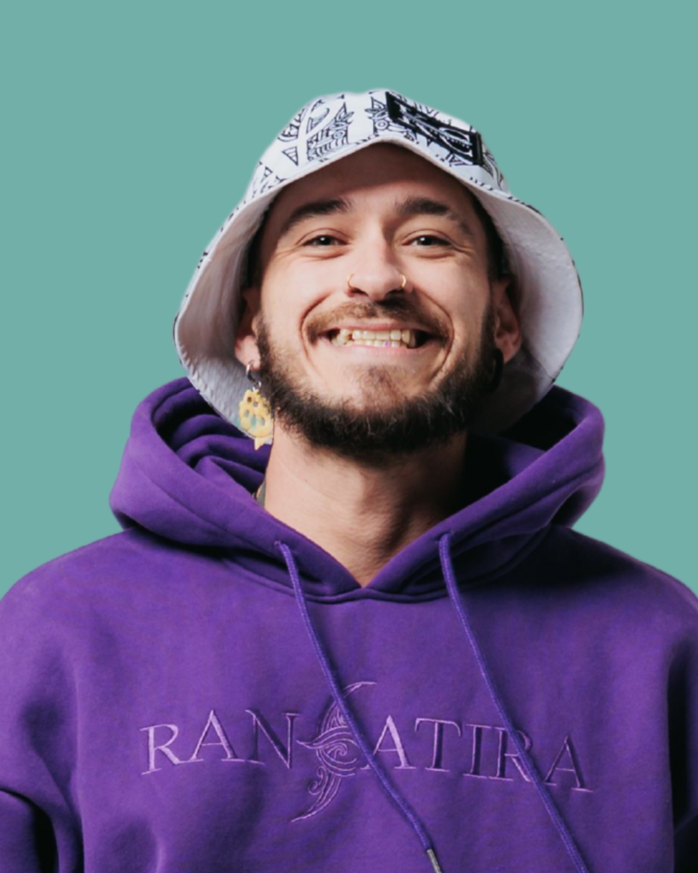 A smiling man wearing a white bucket hat with black print, large earrings, a nose ring, and a purple hoodie with "RANATIRA" written on it, against a teal background.