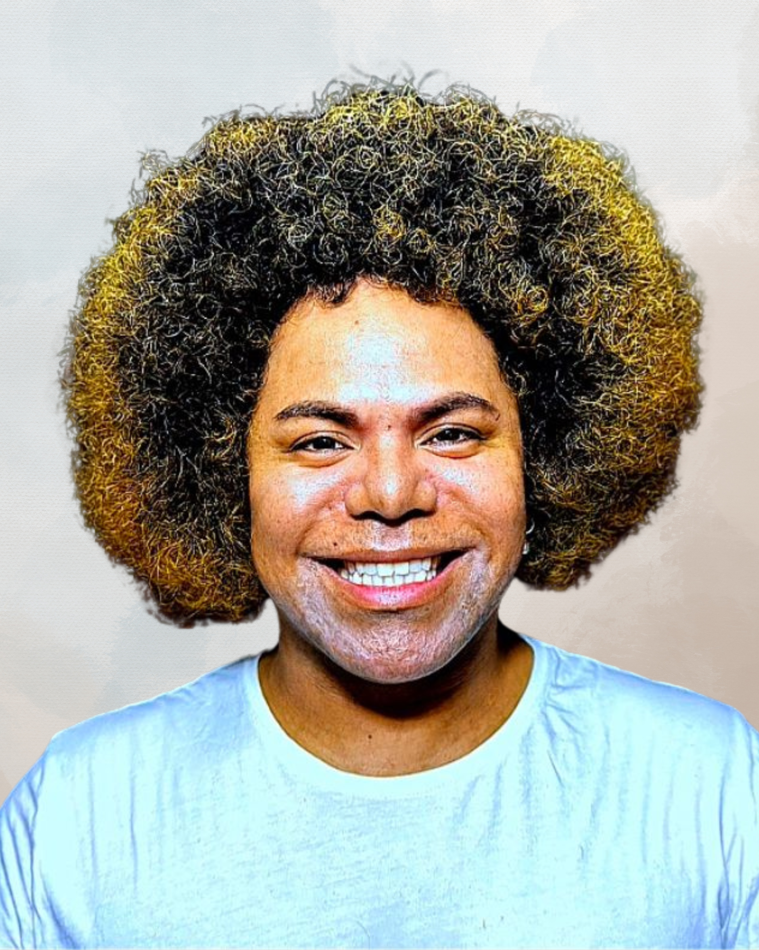 A person with curly, voluminous hair smiling at the camera, wearing a light blue shirt, against a plain light background.