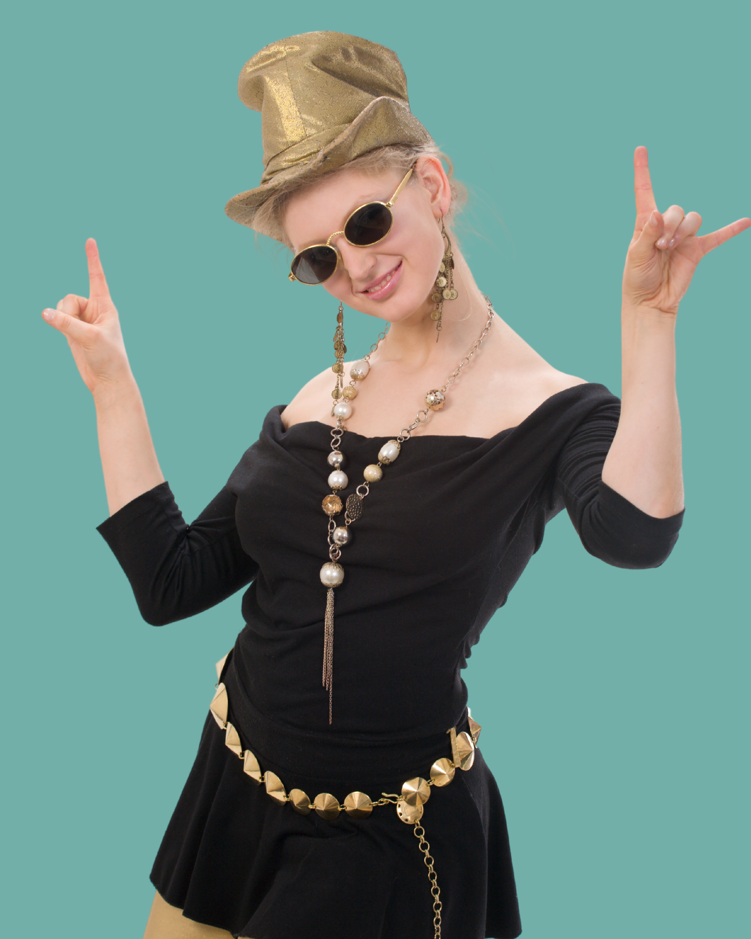 Woman dressed in a costume with a gold hat, sunglasses, and jewelry, making a rock and roll hand gesture.