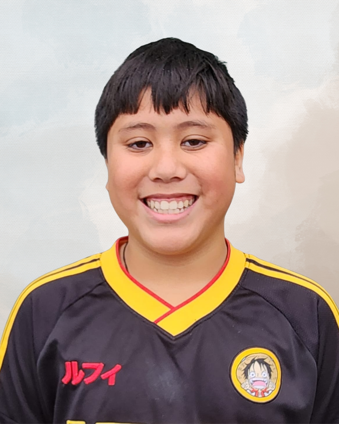 A smiling boy with black hair, wearing a black and yellow sports jersey with Japanese characters and an anime character patch.