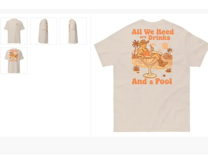 A white T-shirt featuring an orange graphic of a woman relaxing in a pool drink with palm trees in the background and the text "All We Need are Drinks And a Pool."