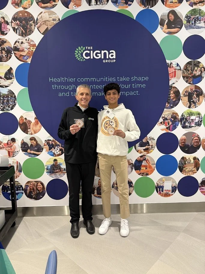 Cookie for a Cause founder Vihaan Kamath with Cigna Group CEO David Cordani, recognized for teen-led nonprofit fundraising to support children's healthcare