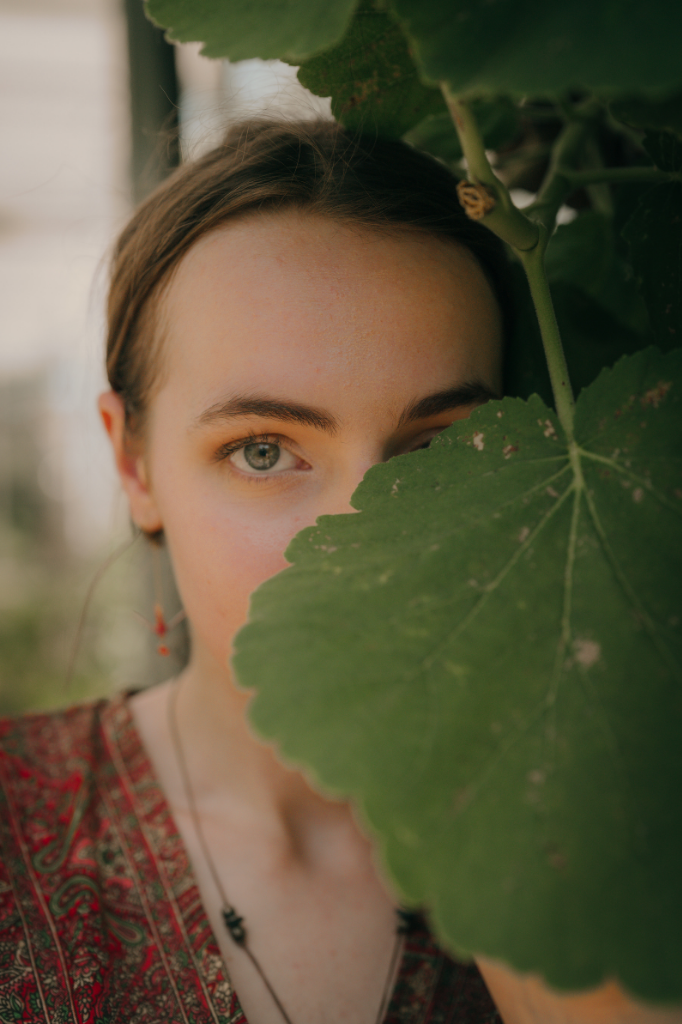Leoni Fretwell's portrait, partially covered by a large leaf looking to camera