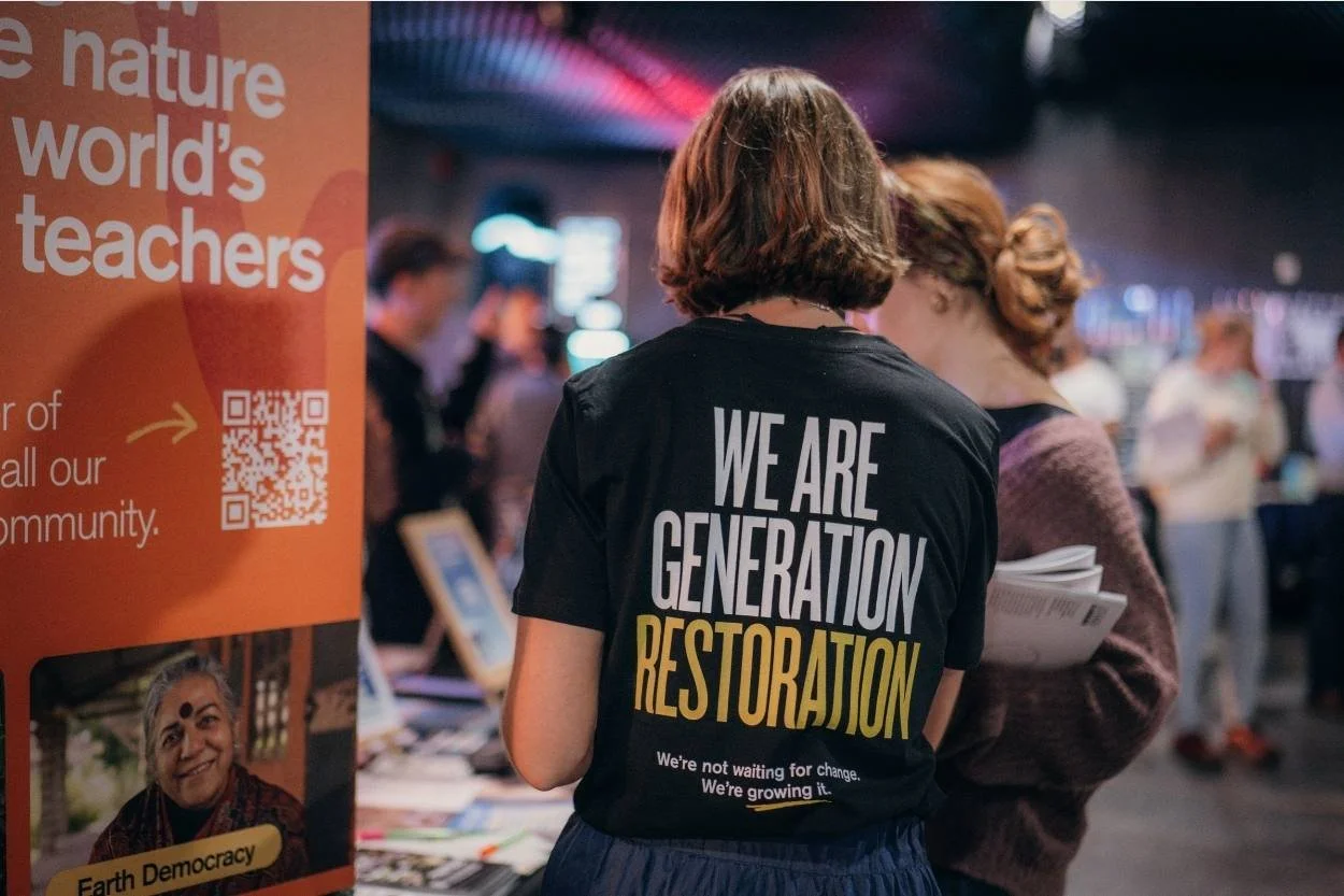 A person with their back to camera wearing a shirt reading 'We Are Generation Restoration'
