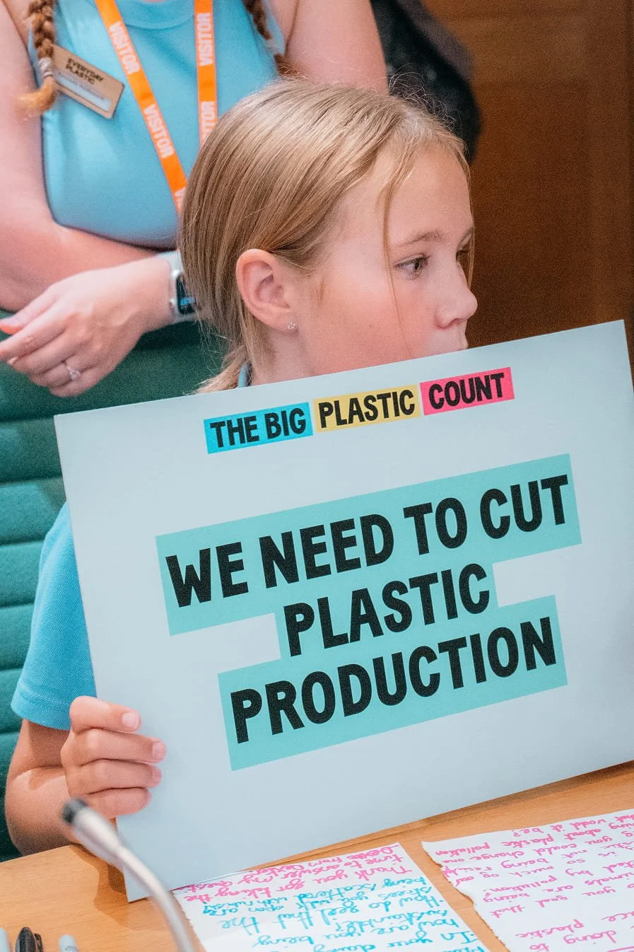 A young student holding a placard saying 'we need to cut plastic production'