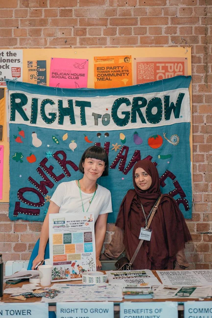 Two people posing in front of an embroidered poster reading 'Right to Grow Tower Hamlets'