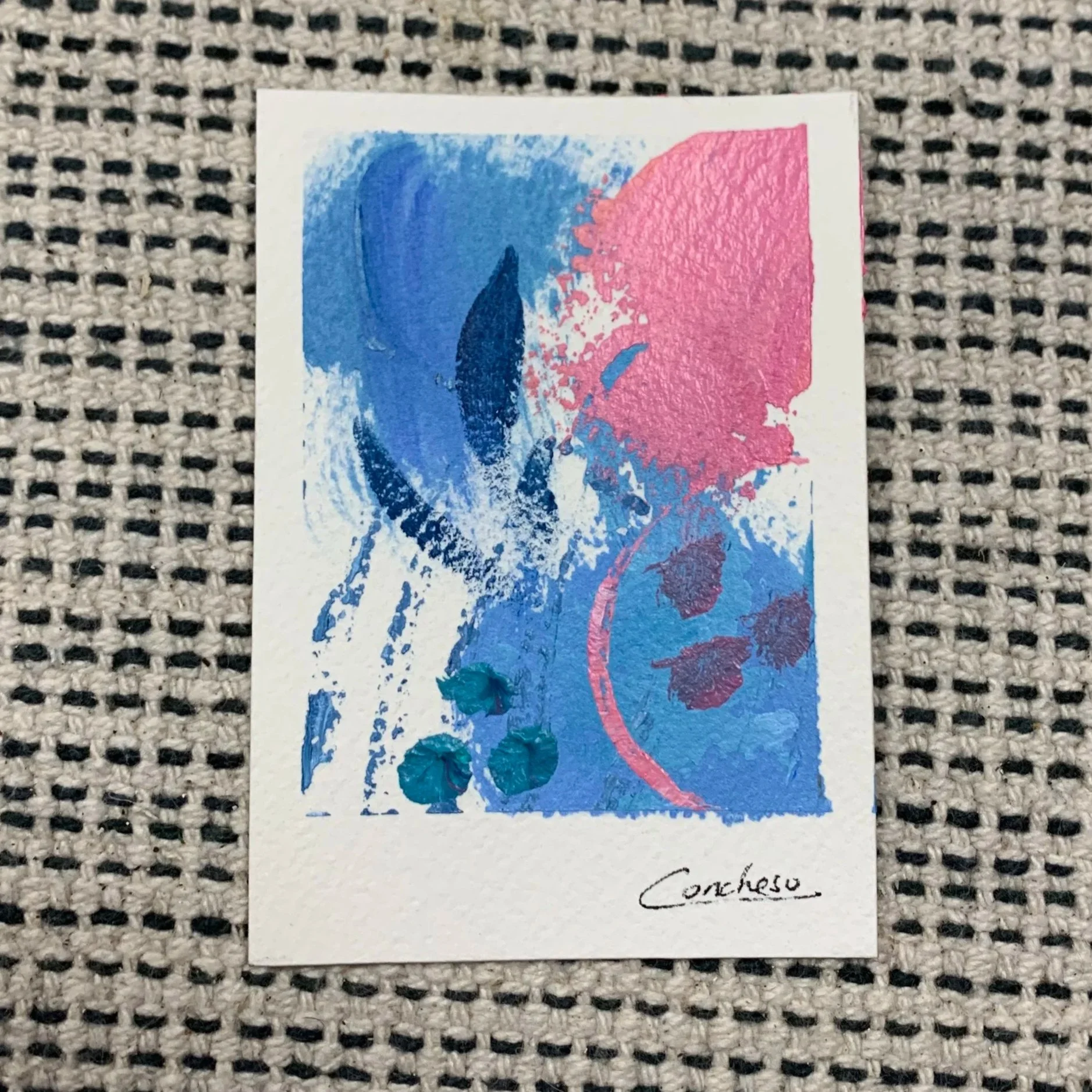 hoja con pintura abstracta en tonos azules y rosados, con firma en la parte inferior que dice 'Corteso'