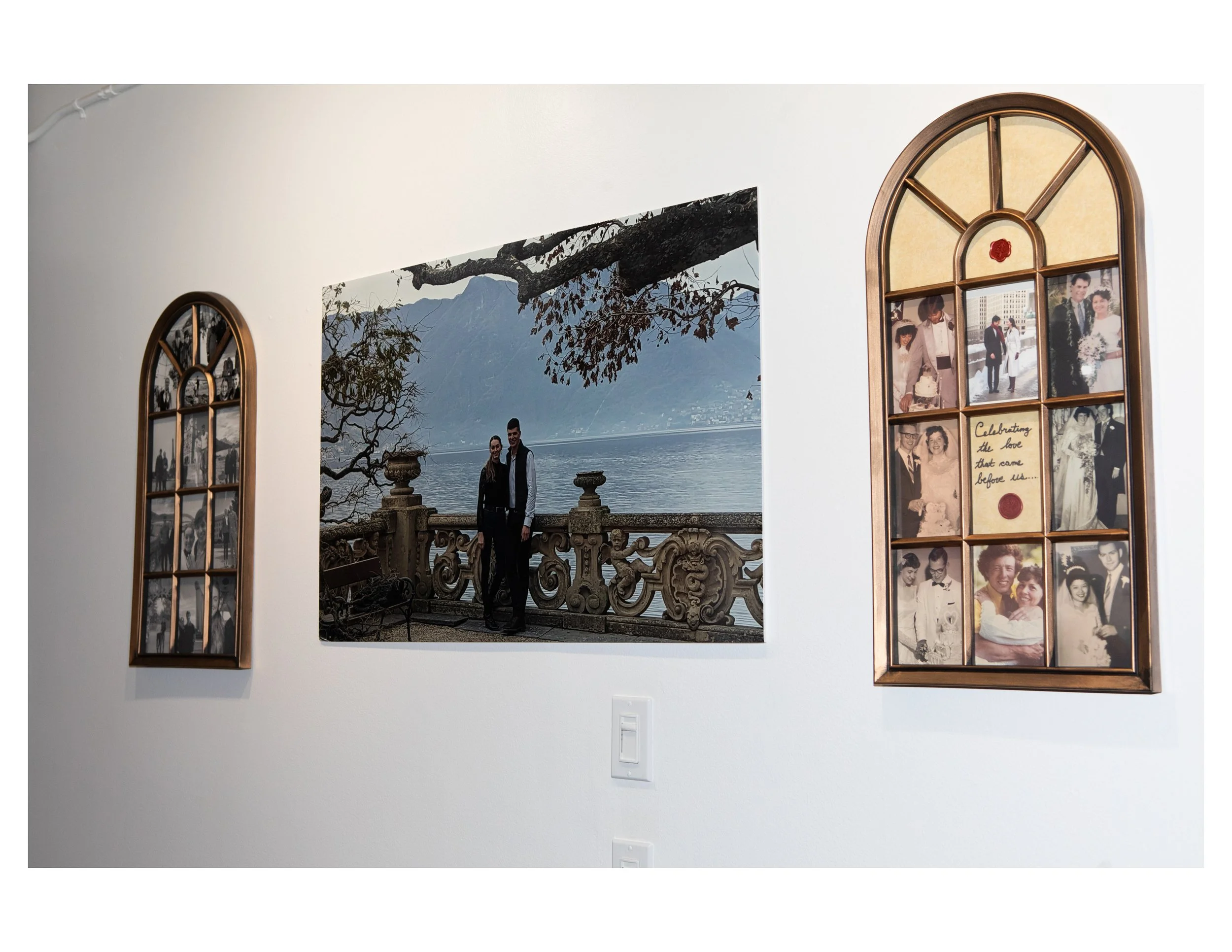 Gallery wall featuring a large photograph of a couple by a body of water, framed child and adult photos, and decorative elements.